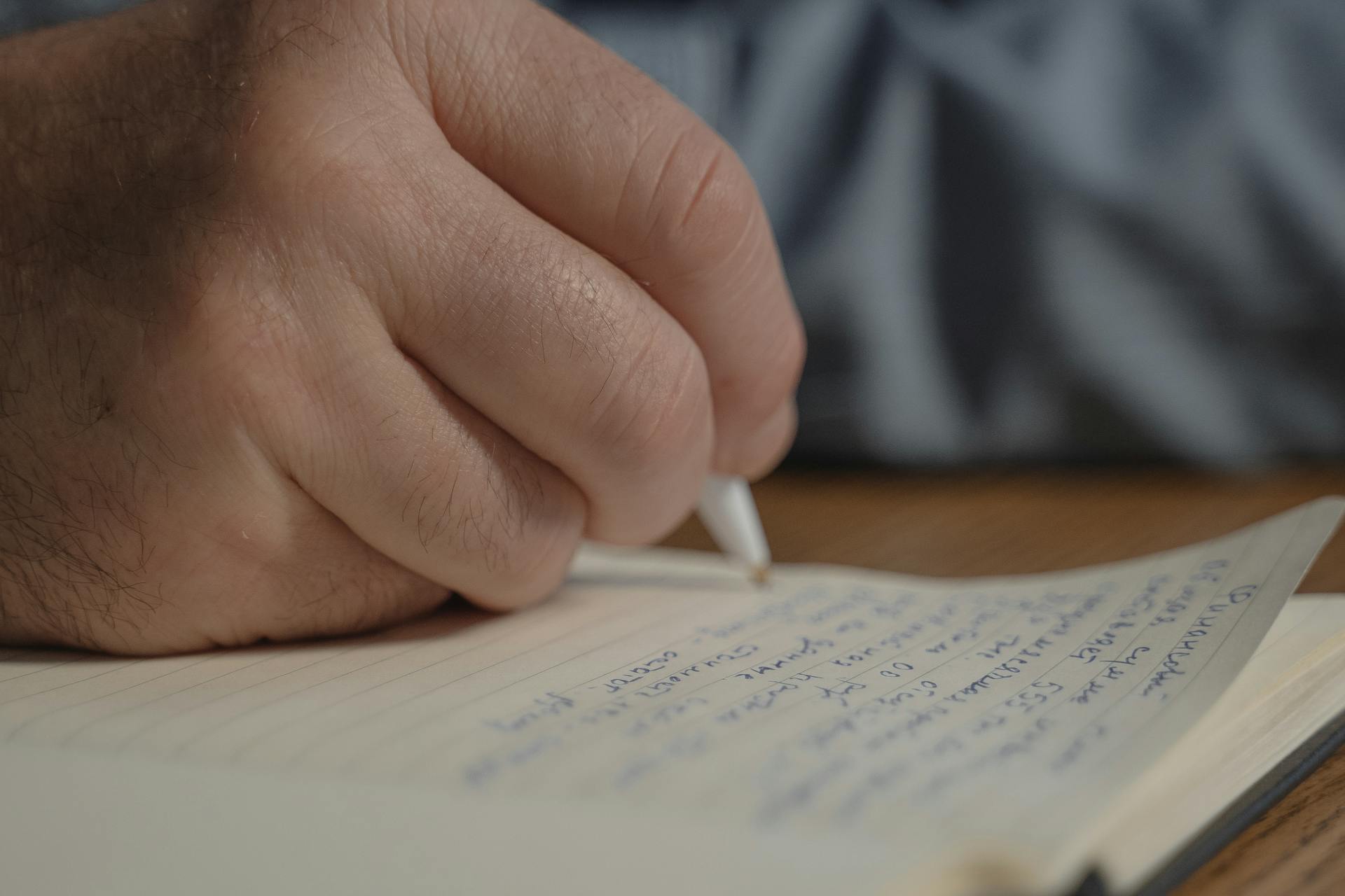 Una persona escribiendo en un papel | Fuente: Pexels