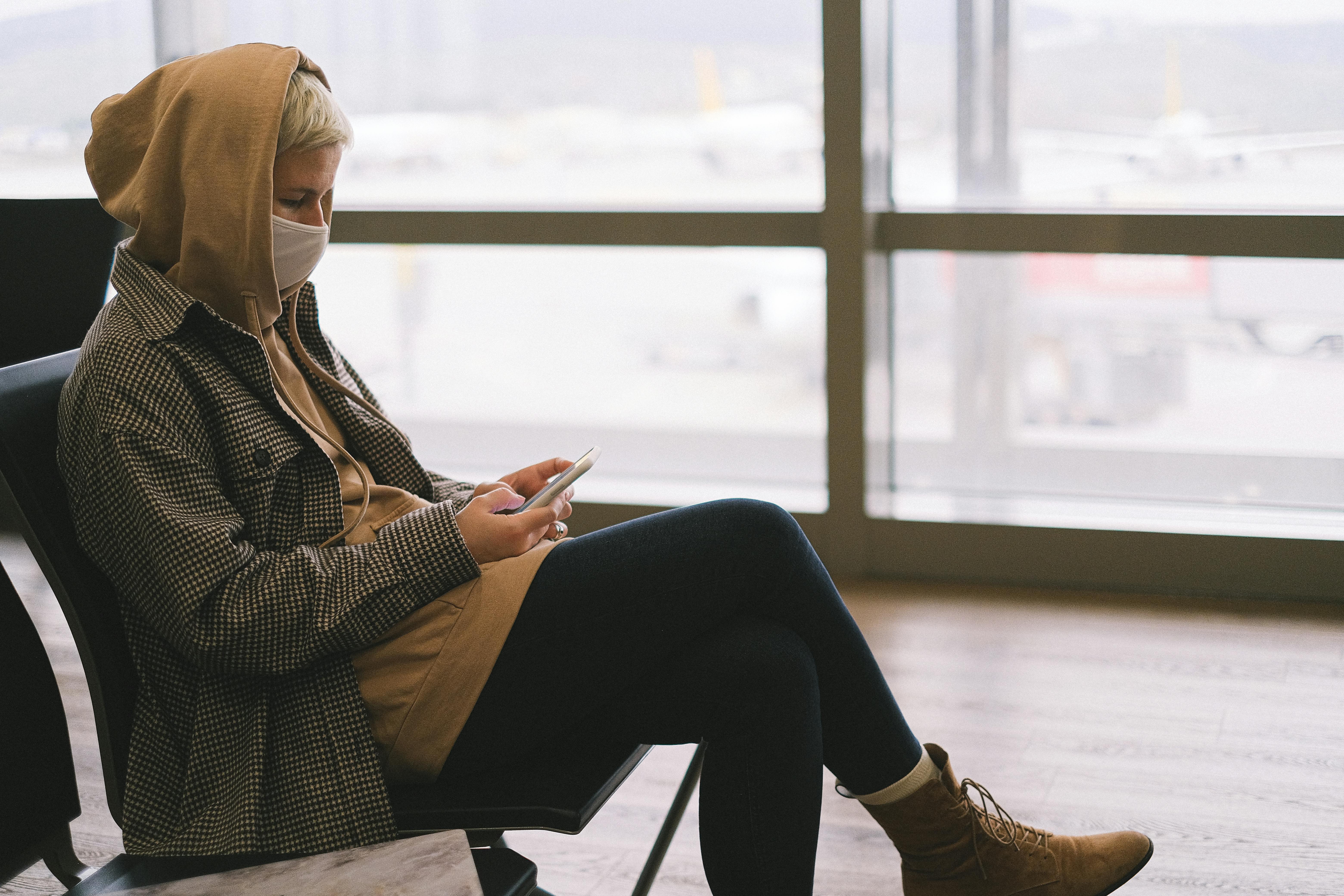 Una mujer usando su teléfono en un aeropuerto | Fuente: Pexels