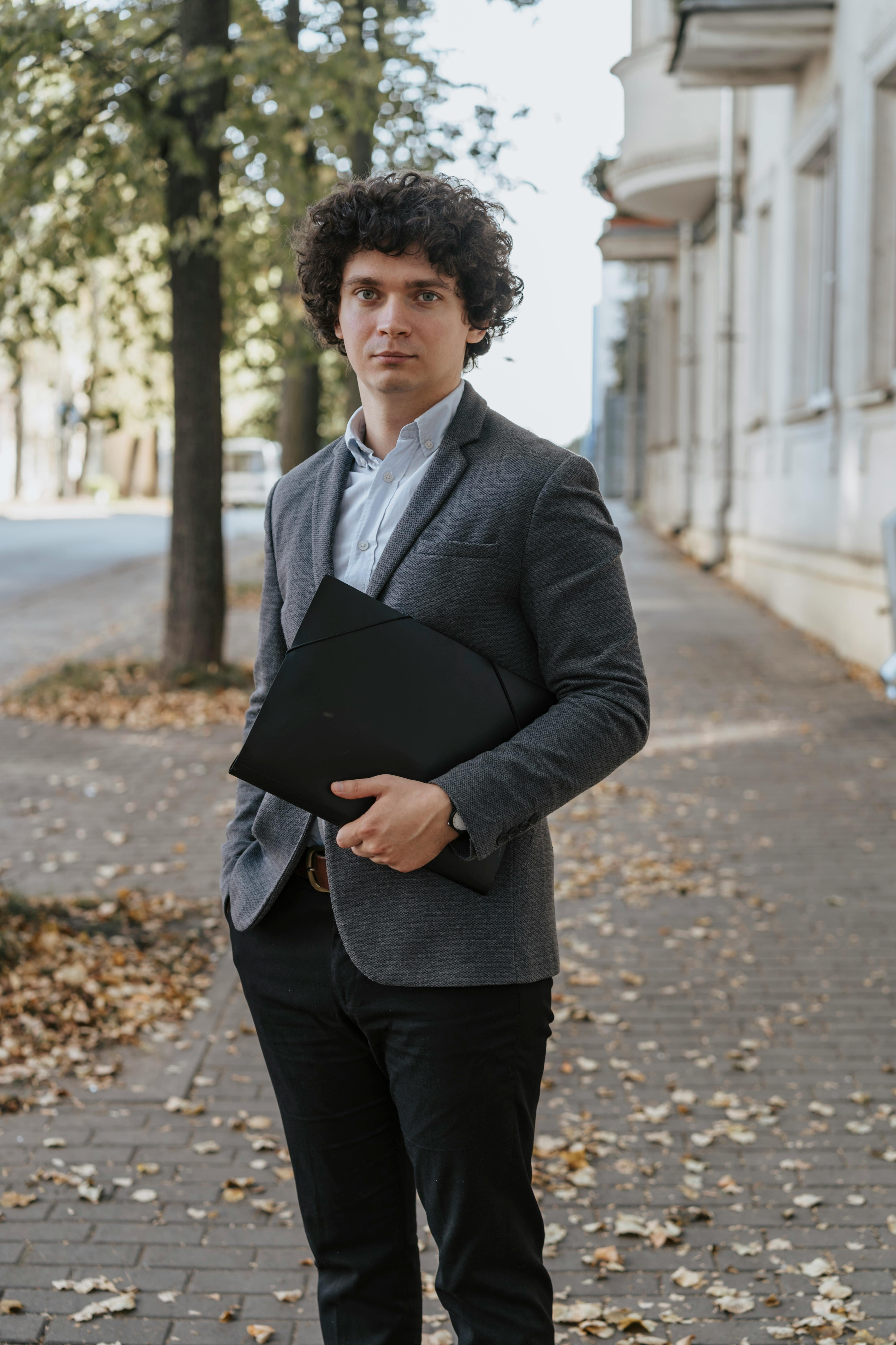 Un hombre sujetando una carpeta de cuero | Fuente: Pexels