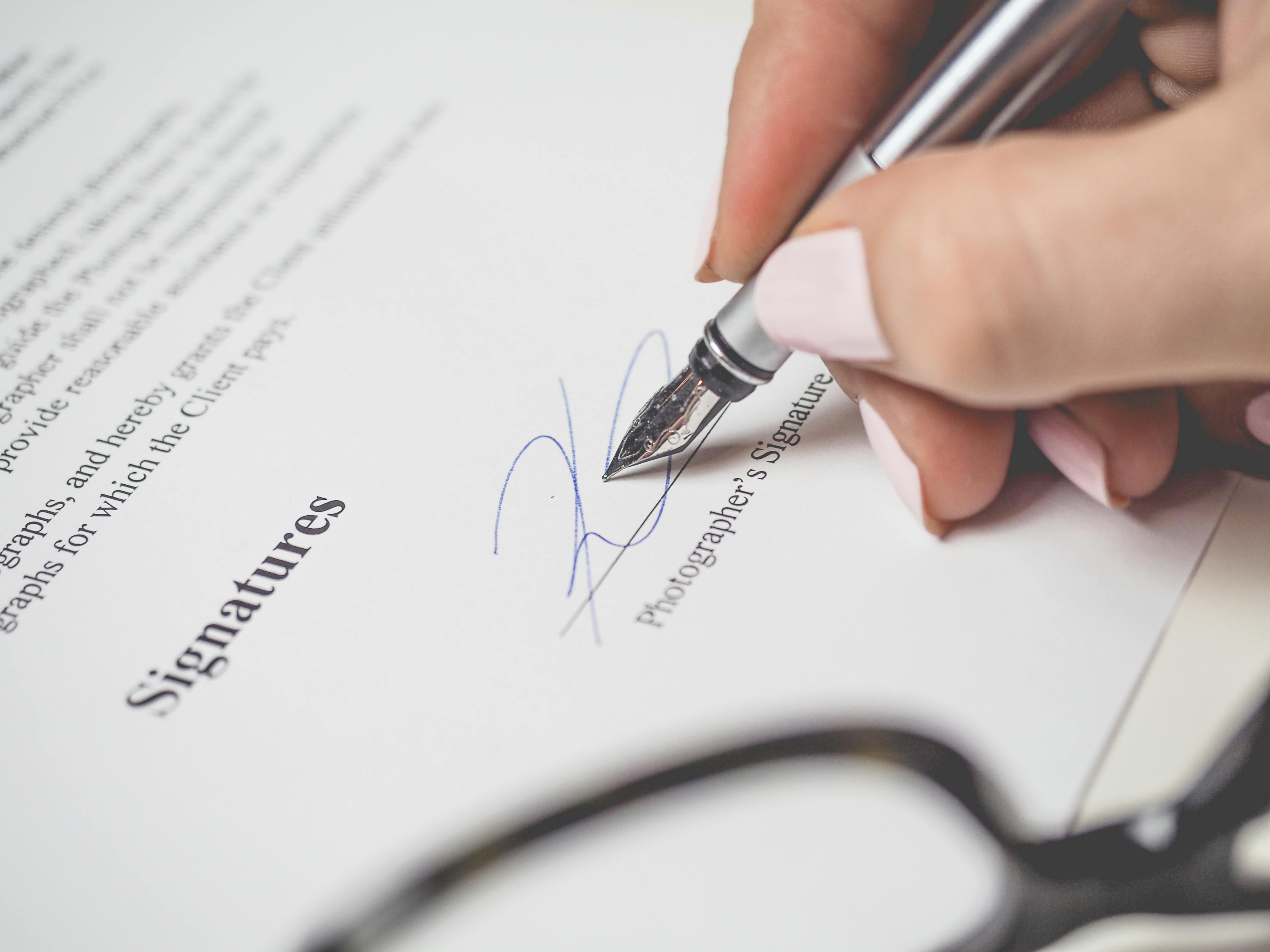 Una persona firmando un documento | Fuente: Pexels