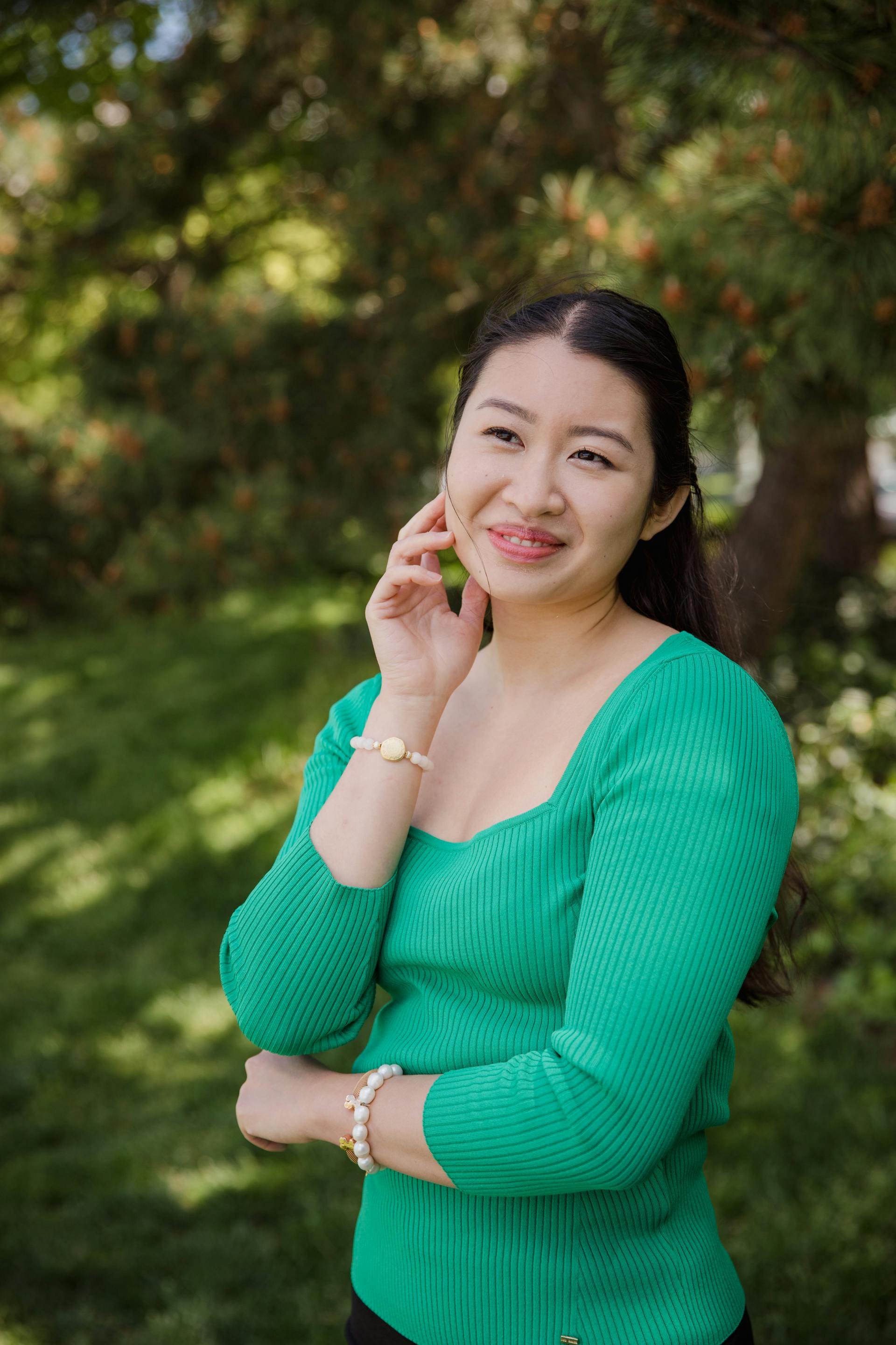 Una bella mujer vestida con una camisa verde y sonriendo al aire libre | Fuente: Pexels