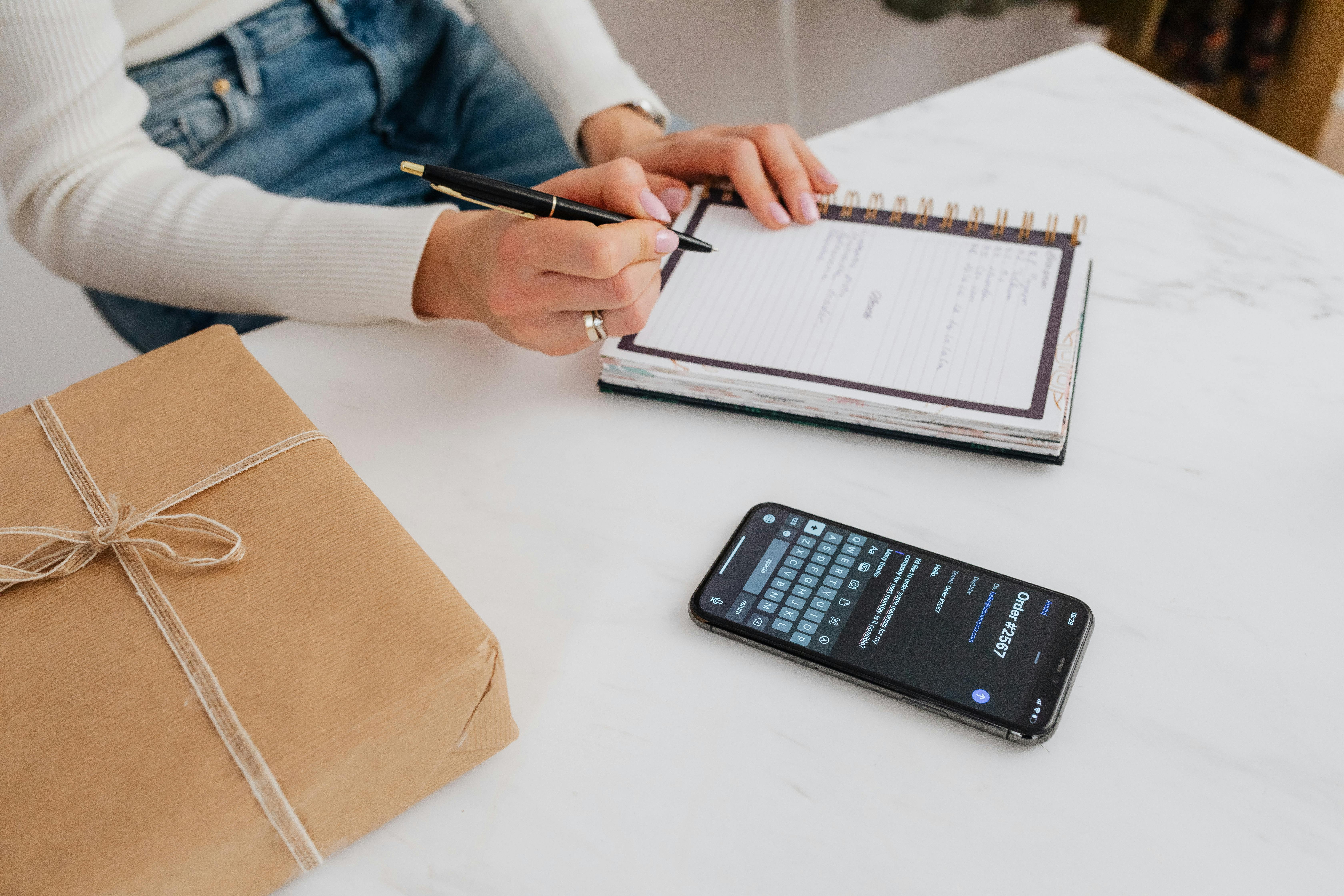 Una persona escribiendo en un cuaderno blanco | Fuente: Pexels
