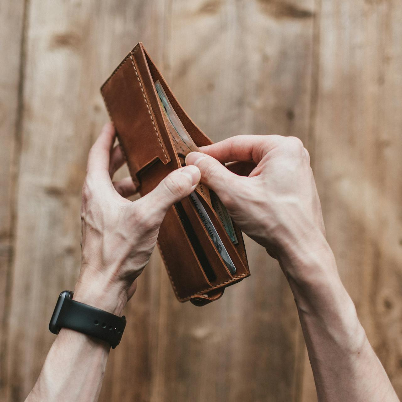 Un hombre sujetando su cartera | Fuente: Pexels