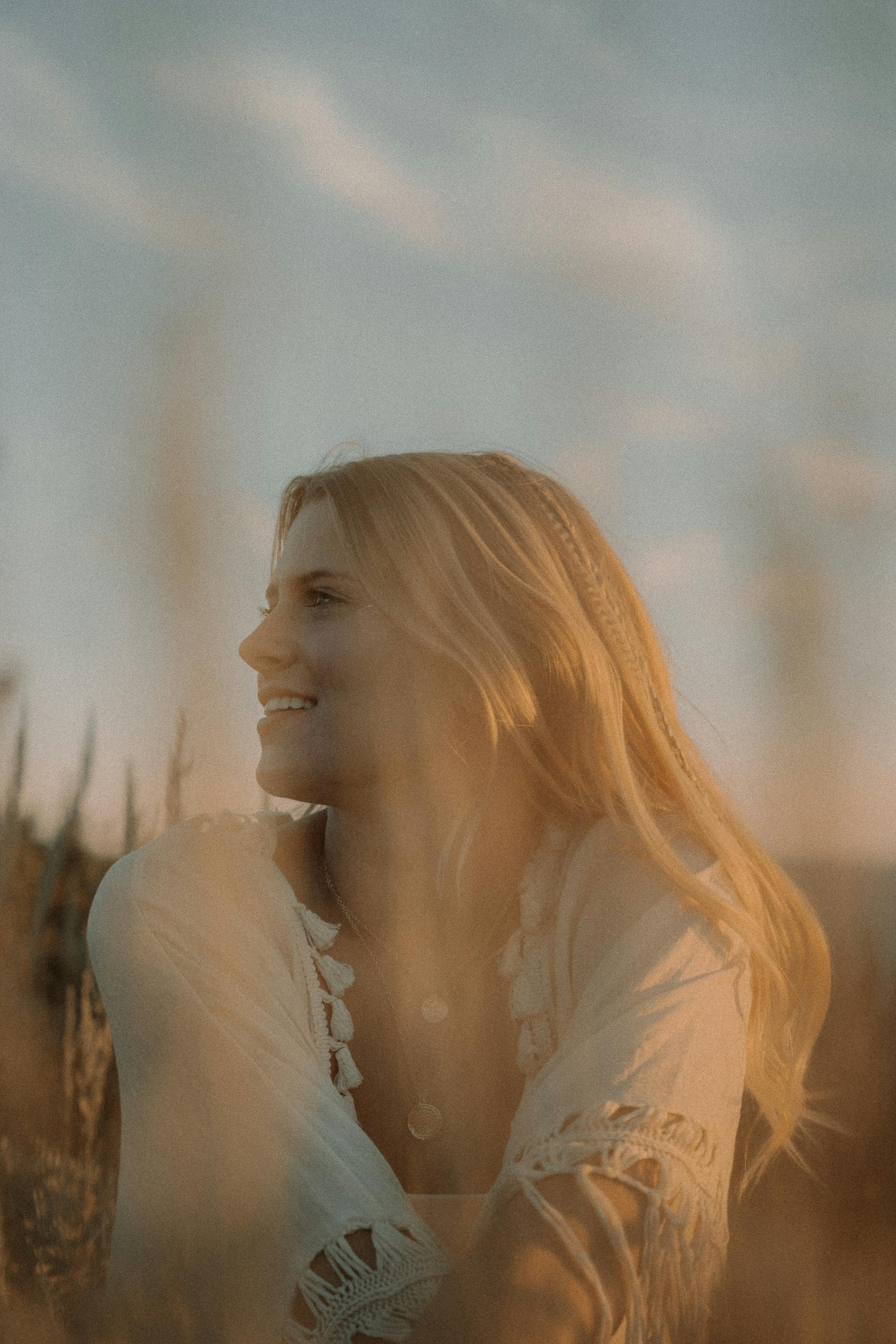 Una mujer feliz sentada al aire libre | Fuente: Pexels
