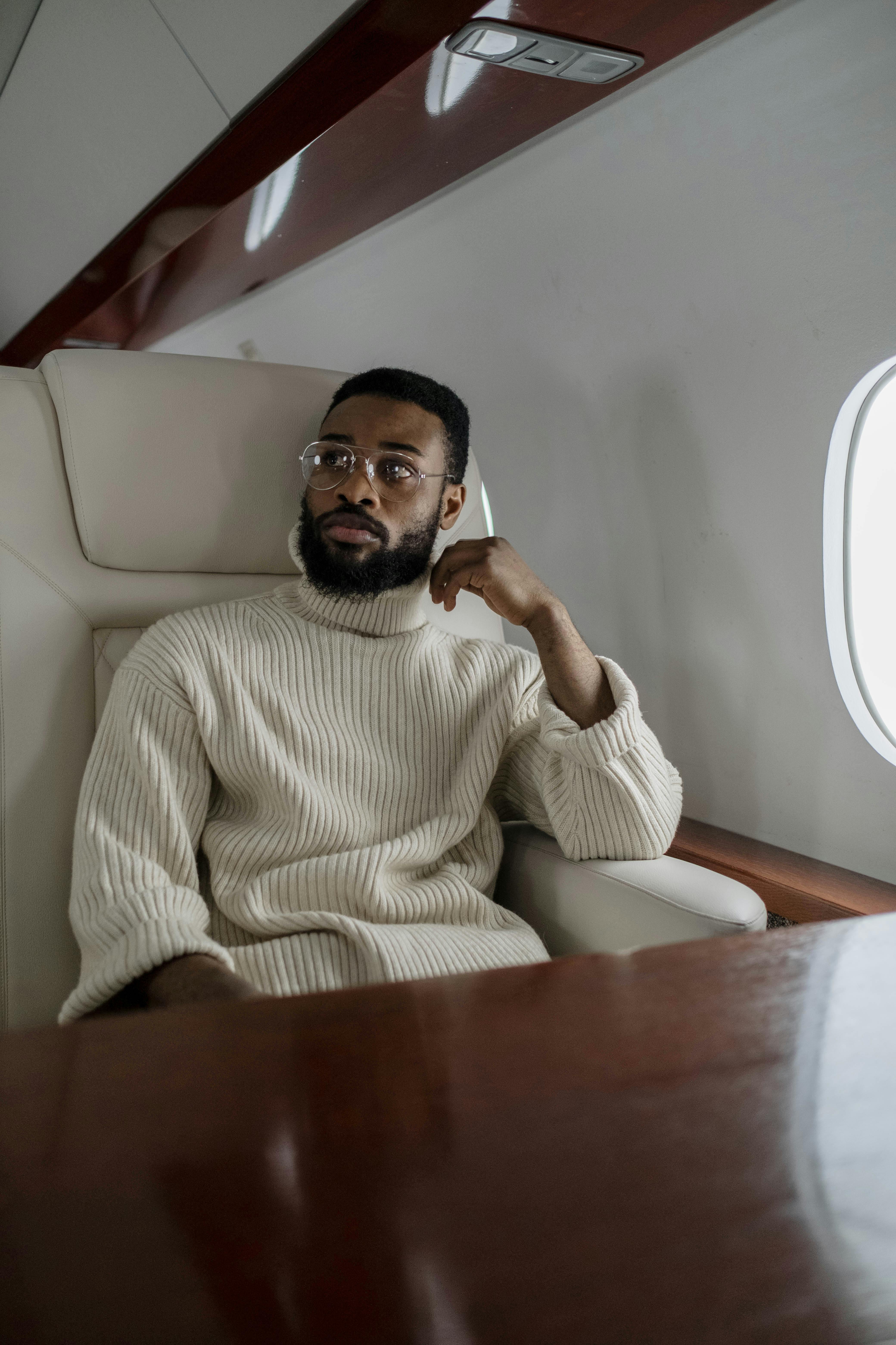 Hombre con jersey beige de cuello alto en el interior de un avión | Fuente: Pexels