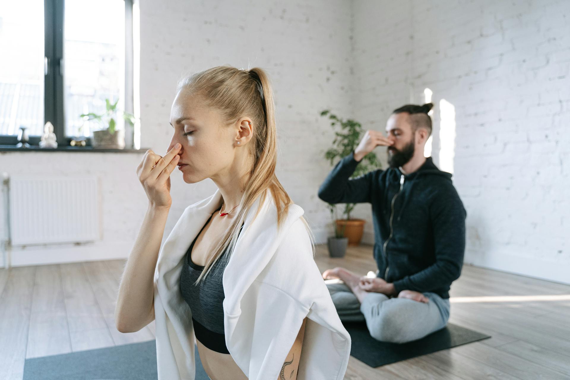 Una pareja practica ejercicios de respiración durante una tranquila sesión de yoga | Fuente: Pexels