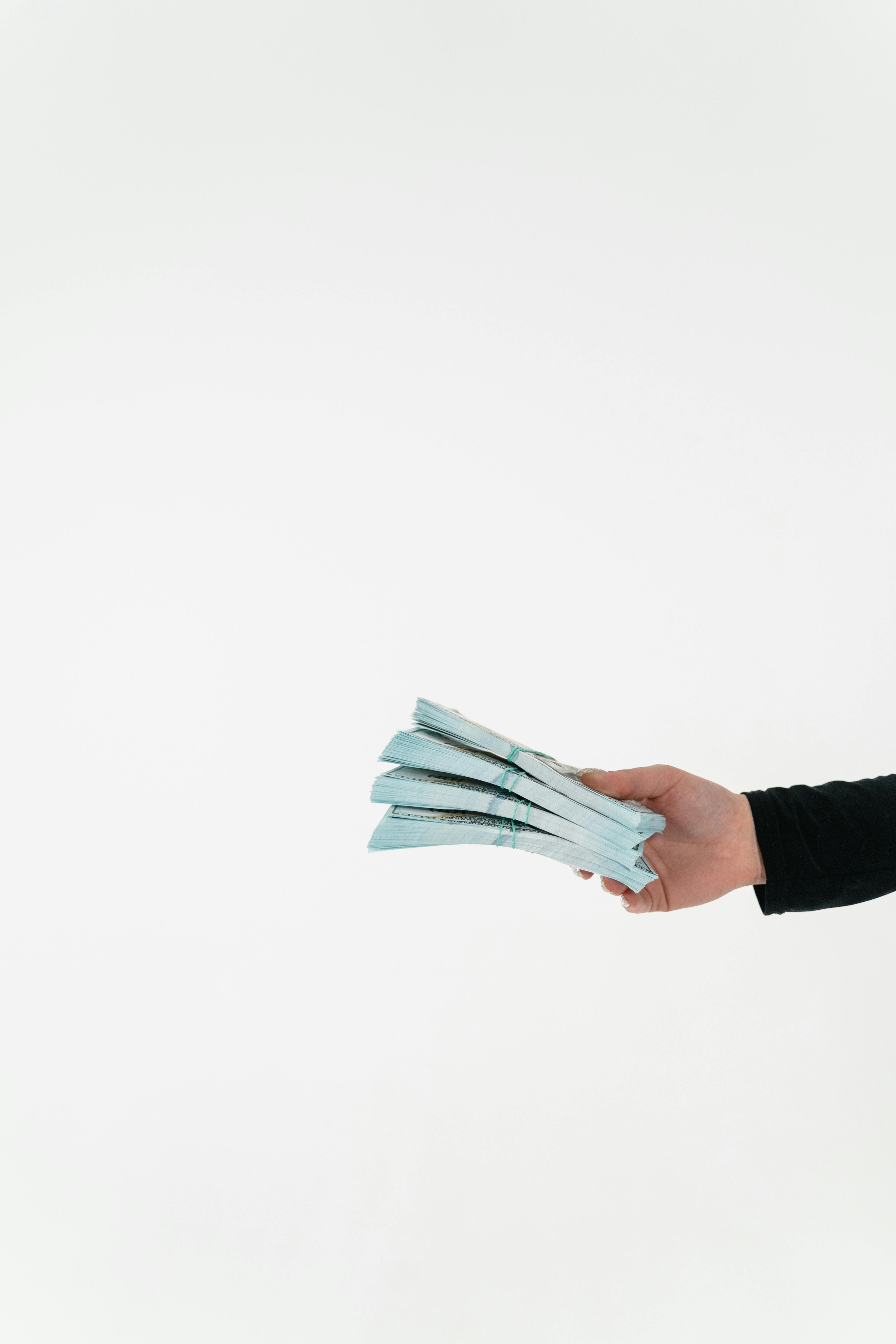 Una persona sosteniendo fajos de billetes | Fuente: Pexels