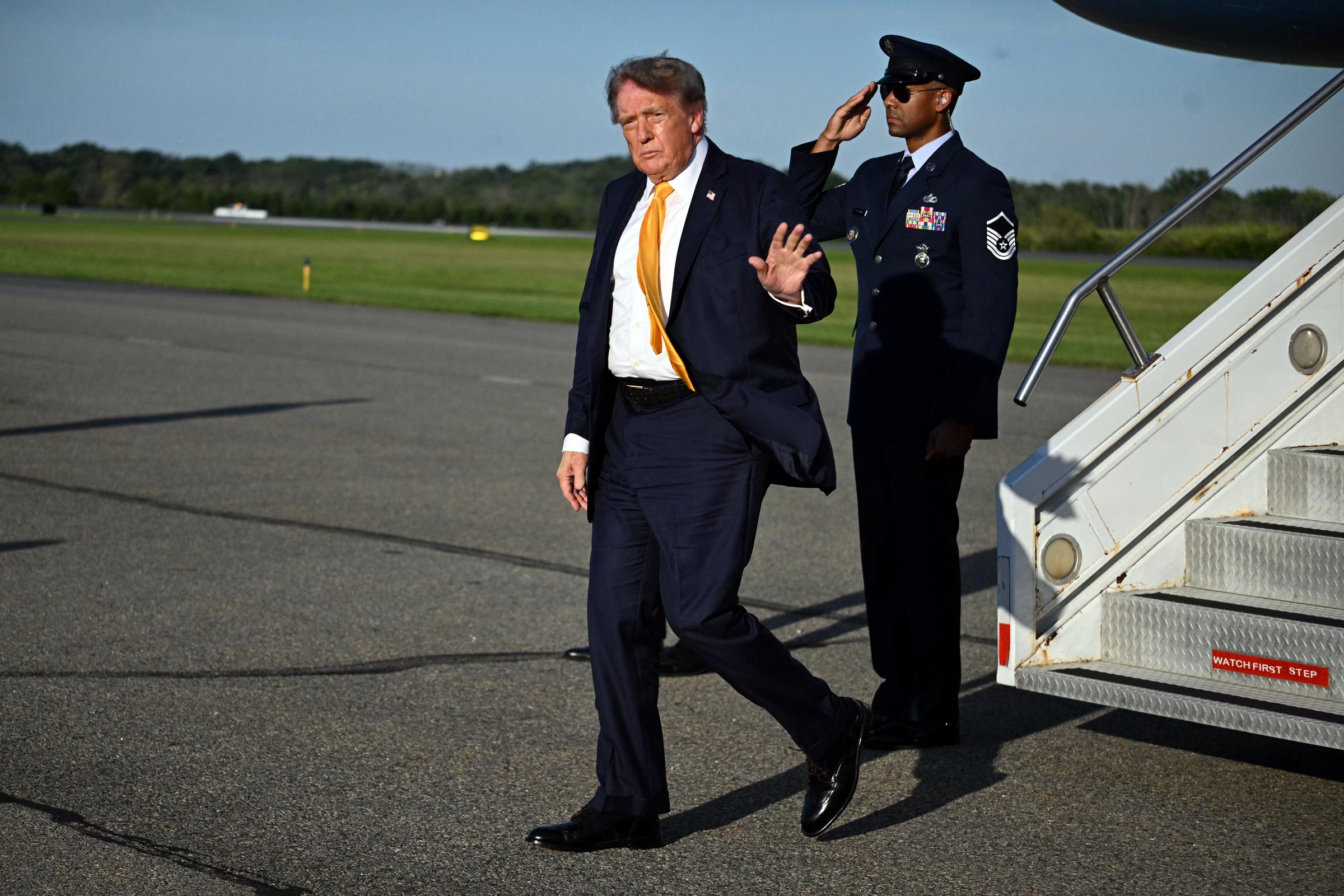 Trump saluda a los periodistas en el Aeropuerto Municipal de Morristown, dejando ver de nuevo los tonos castaños más oscuros que se aprecian en su característico peinado hacia un lado.