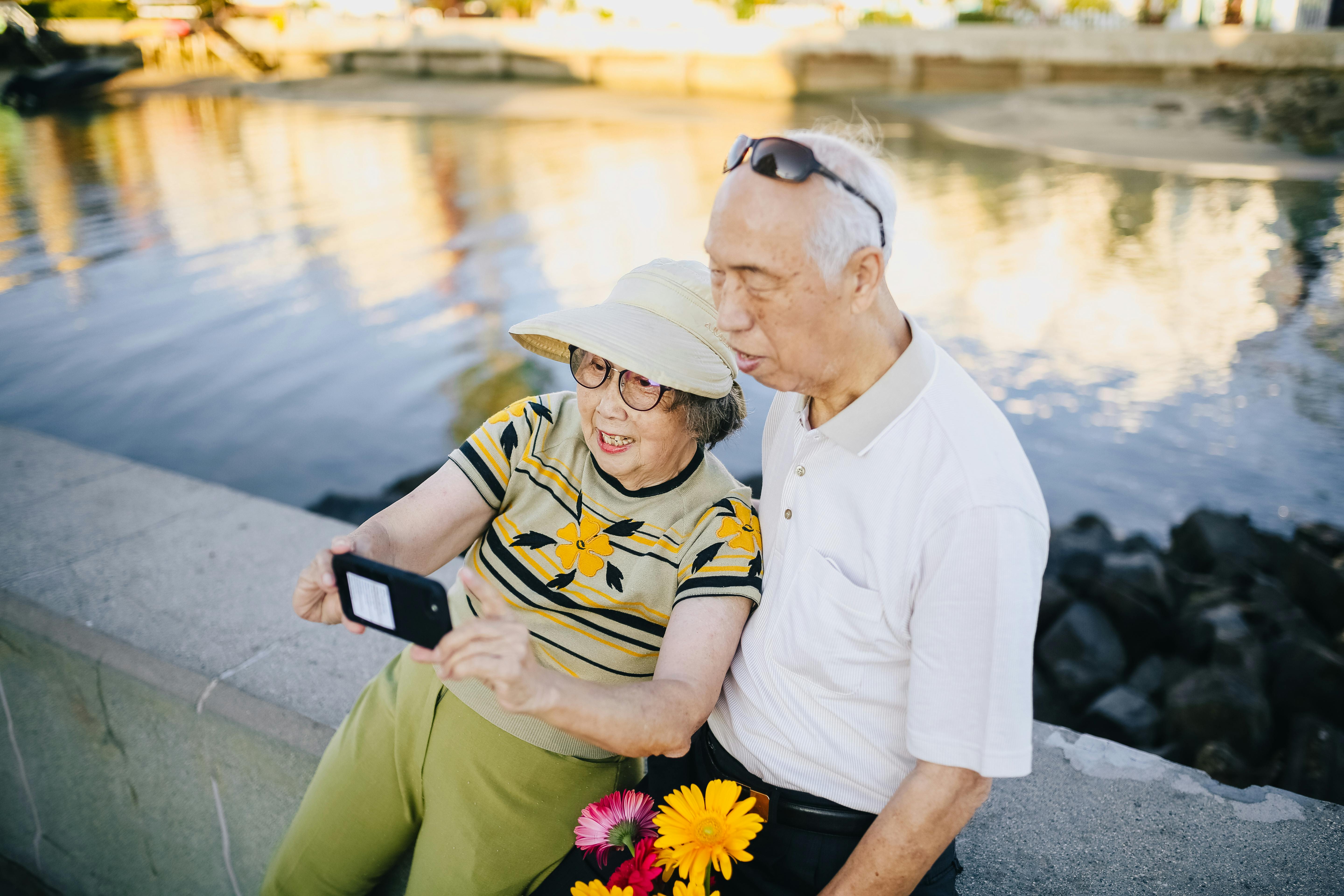 Pareja de ancianos en un banco de cemento tomándose un selfie | Fuente: Pexels