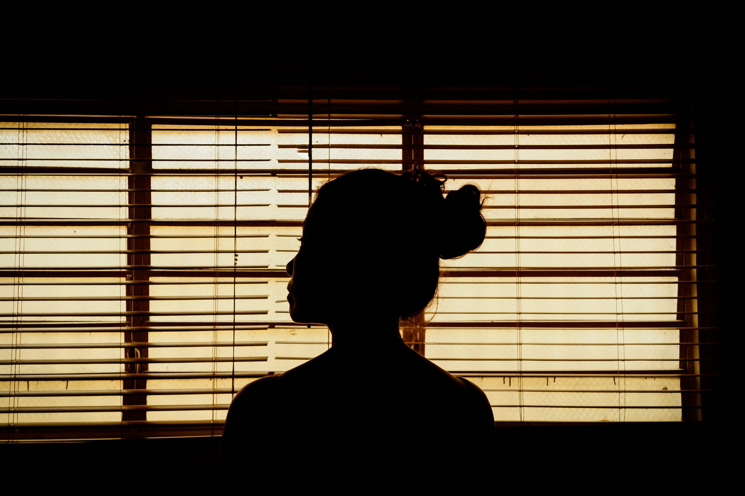 Una persona oculta tras unas persianas | Fuente: Unsplash