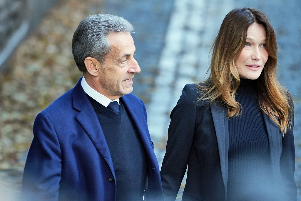 El expresidente francés Nicolas Sarkozy y su esposa Carla Bruni Sarkozy caminan desde su casa hasta el coche que le llevará a la prisión de la Santé para comenzar una condena de cinco años de prisión, en París, el 21 de octubre de 2025. | Fuente: Getty Images