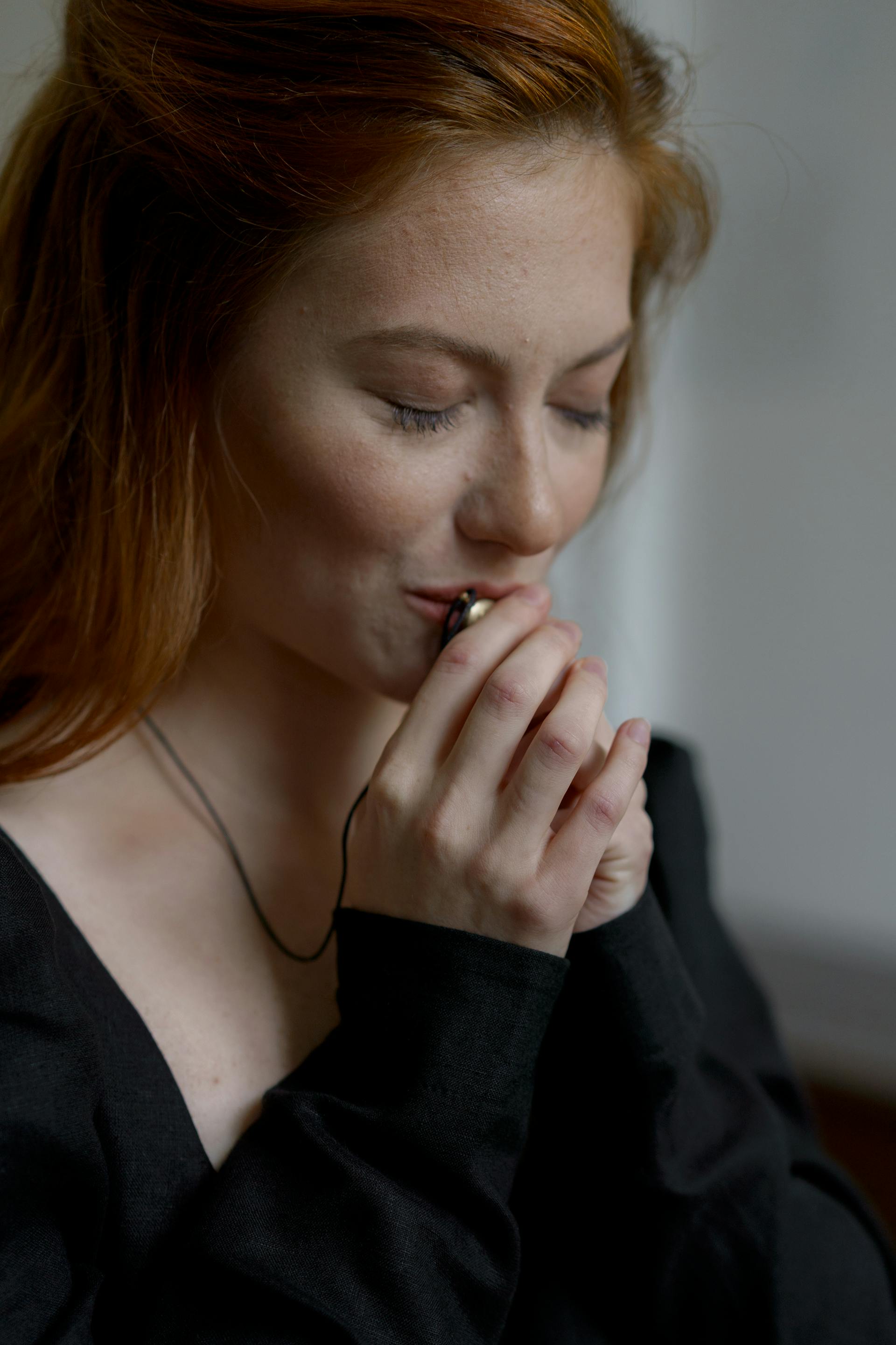Una mujer con un vestido negro besando su collar | Fuente: Pexels