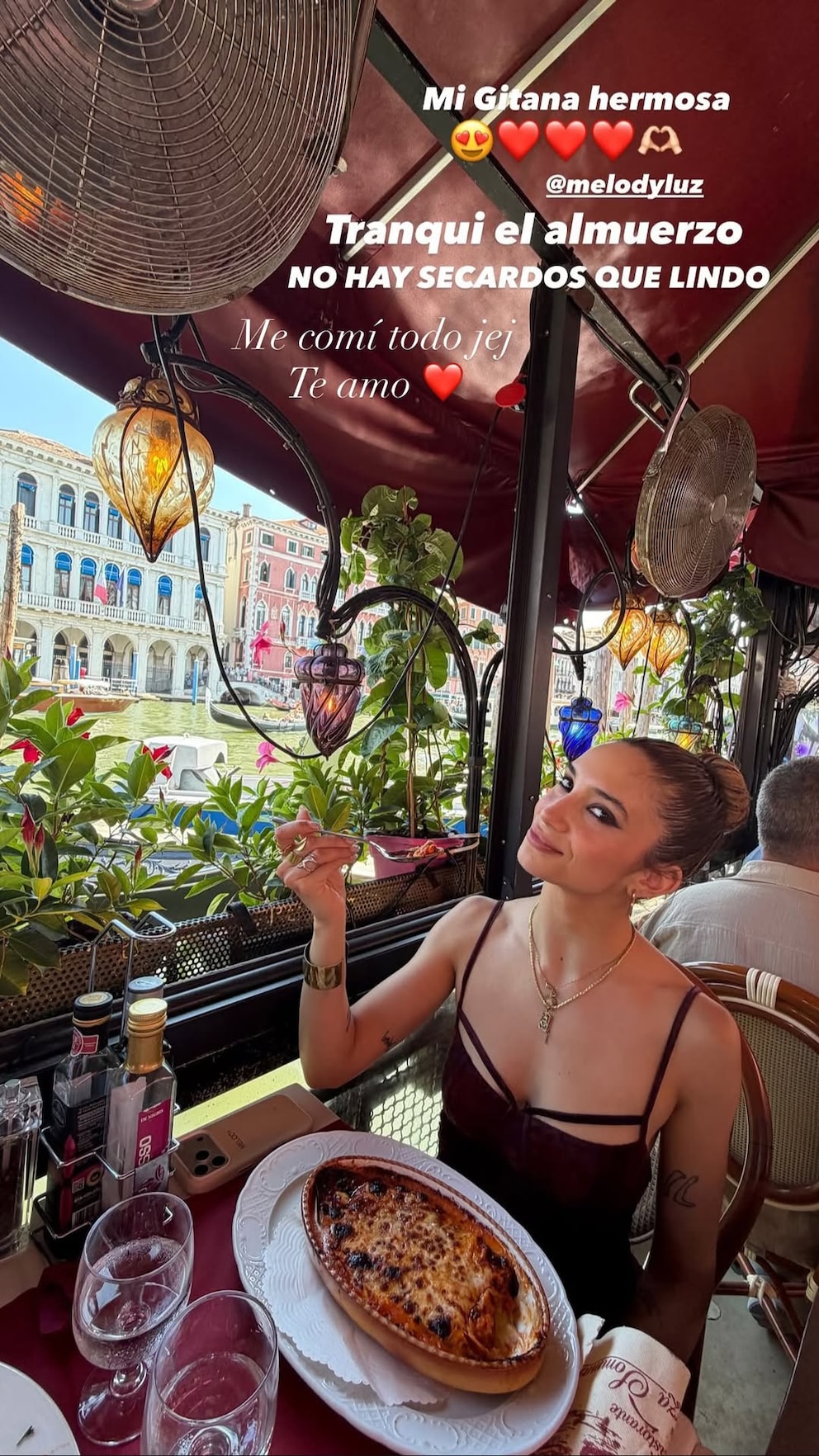 Melody Luz almorzando un plato de lasaña en una terraza frente a un canal en Venecia, Italia | Fuente: Instagram Stories/alexcaniggia