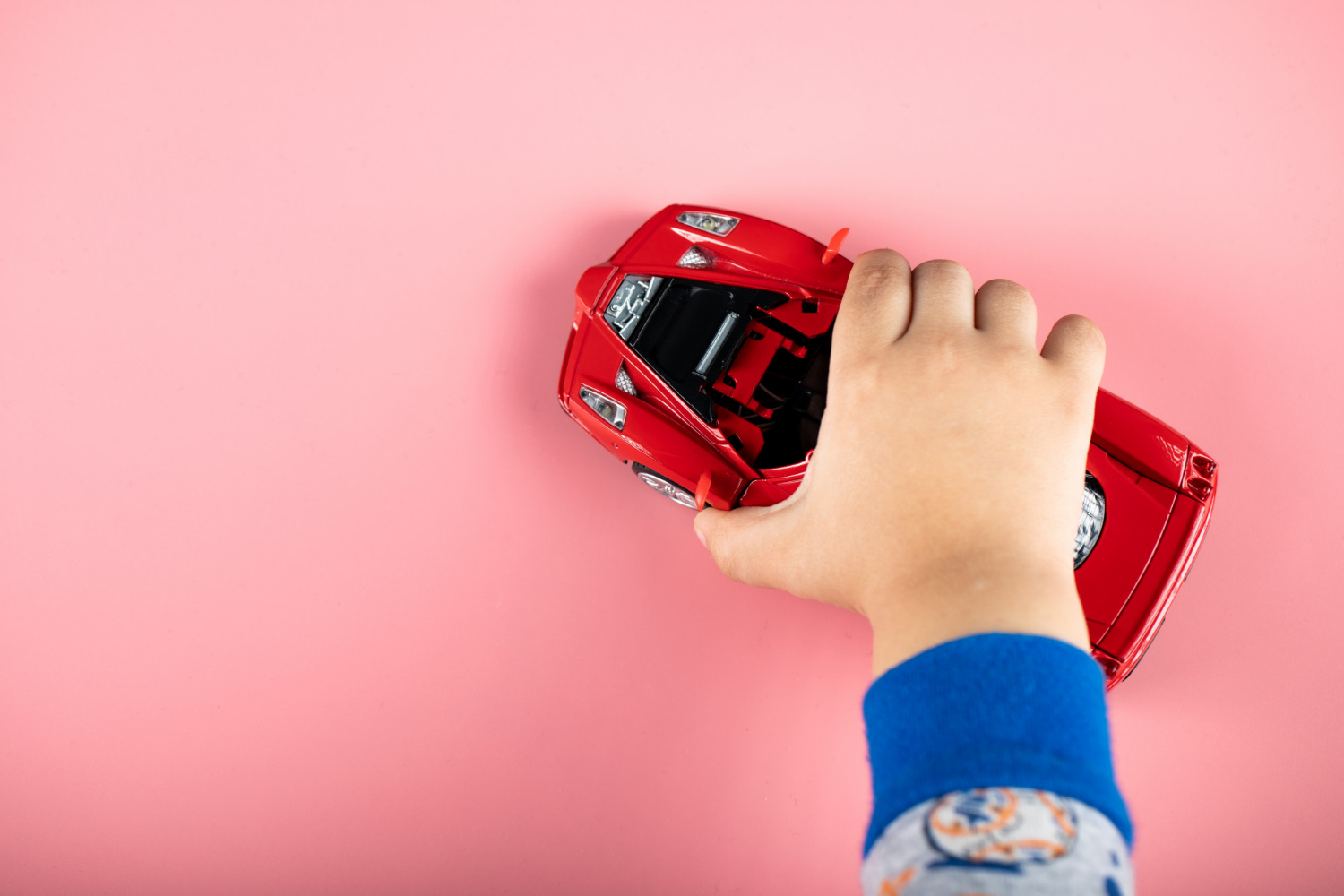 Un niño jugando con un Automóvil rojo de juguete | Fuente: Freepik