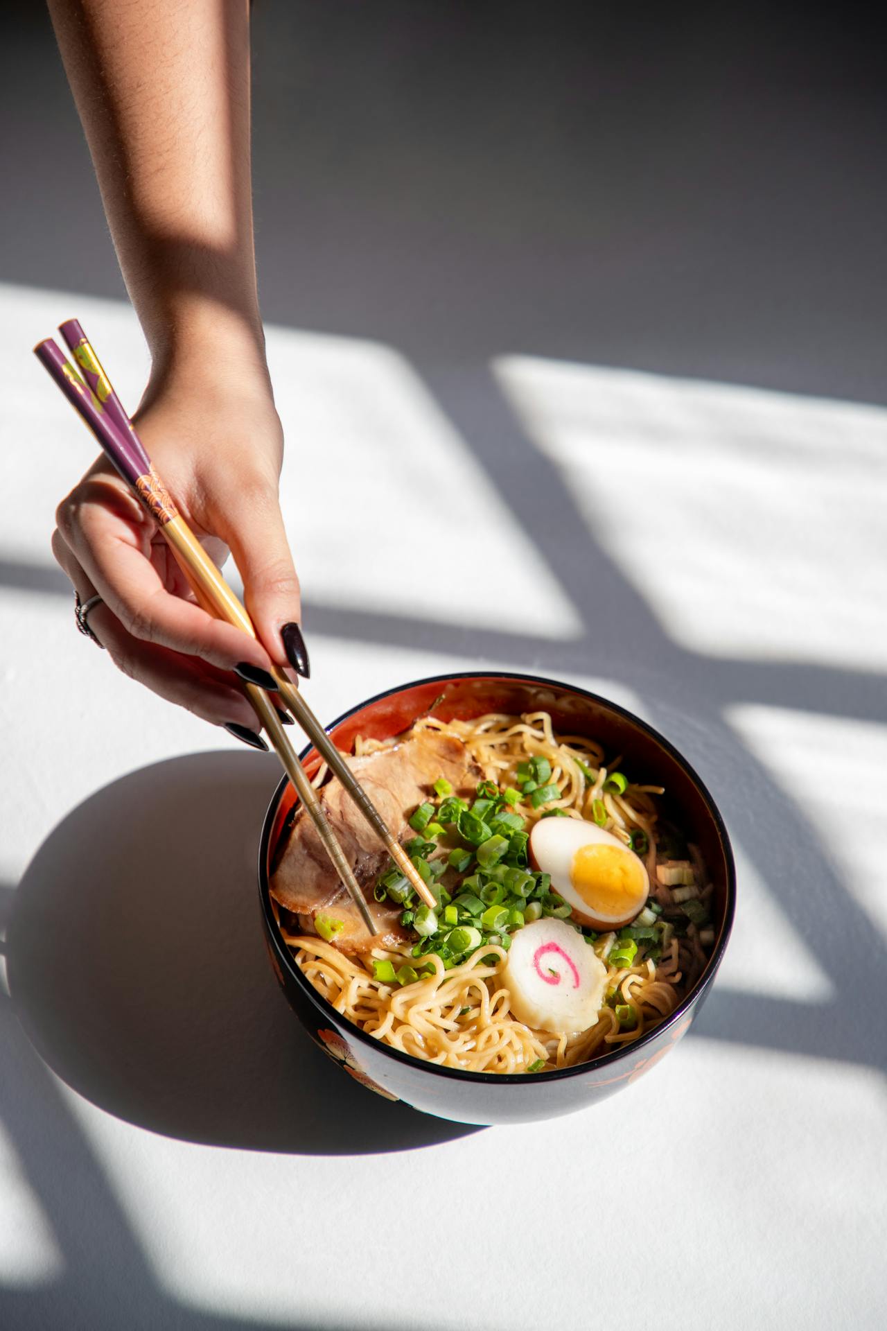 Una mujer con palillos y comiendo ramen | Fuente: Pexels