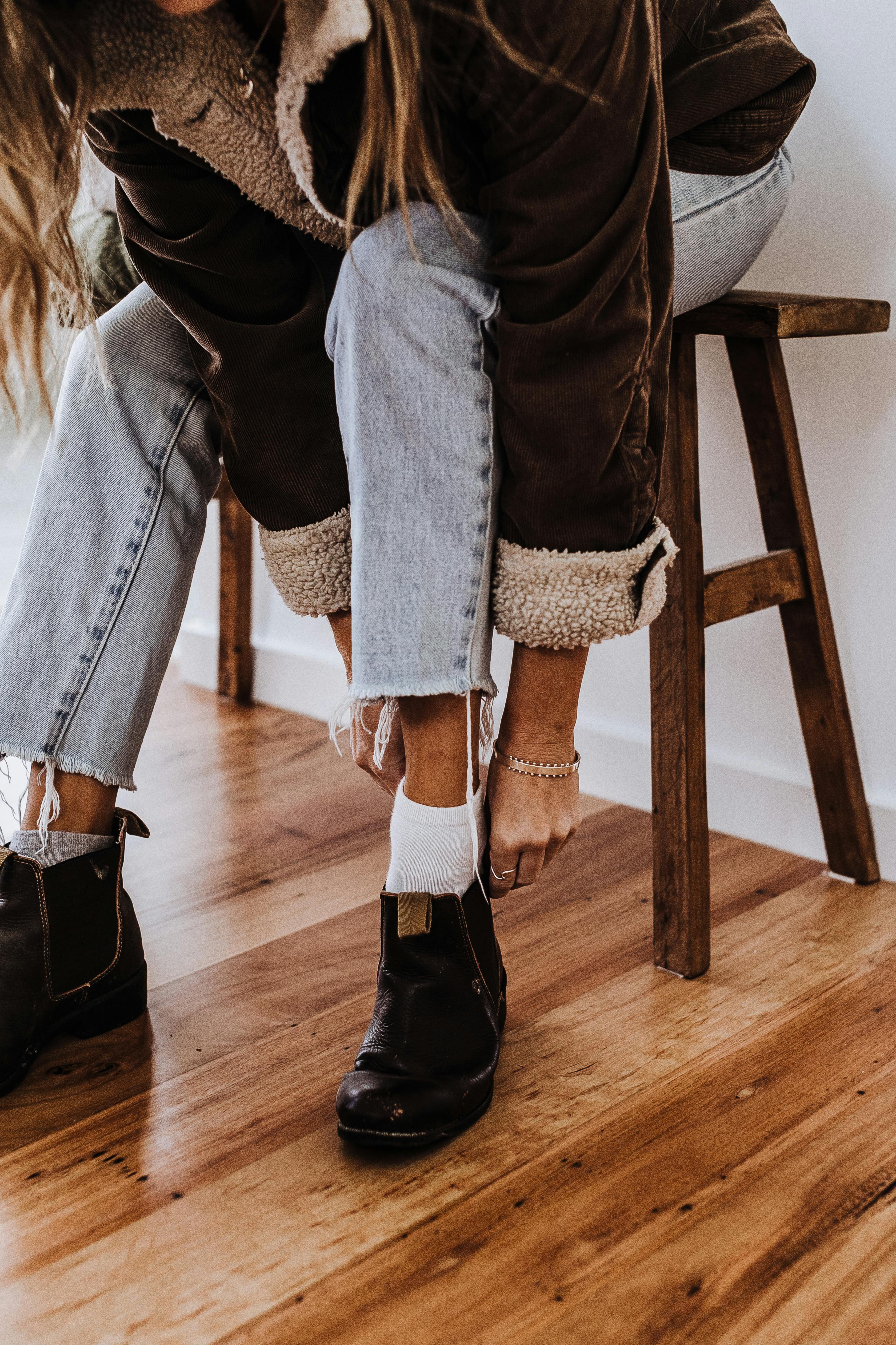 Una mujer poniéndose un par de botas | Fuente: Pexels