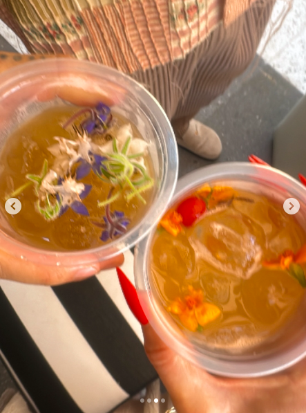 Primer plano de dos personas sujetando bebidas con flores comestibles. | Fuente: Instagram/heidiklum