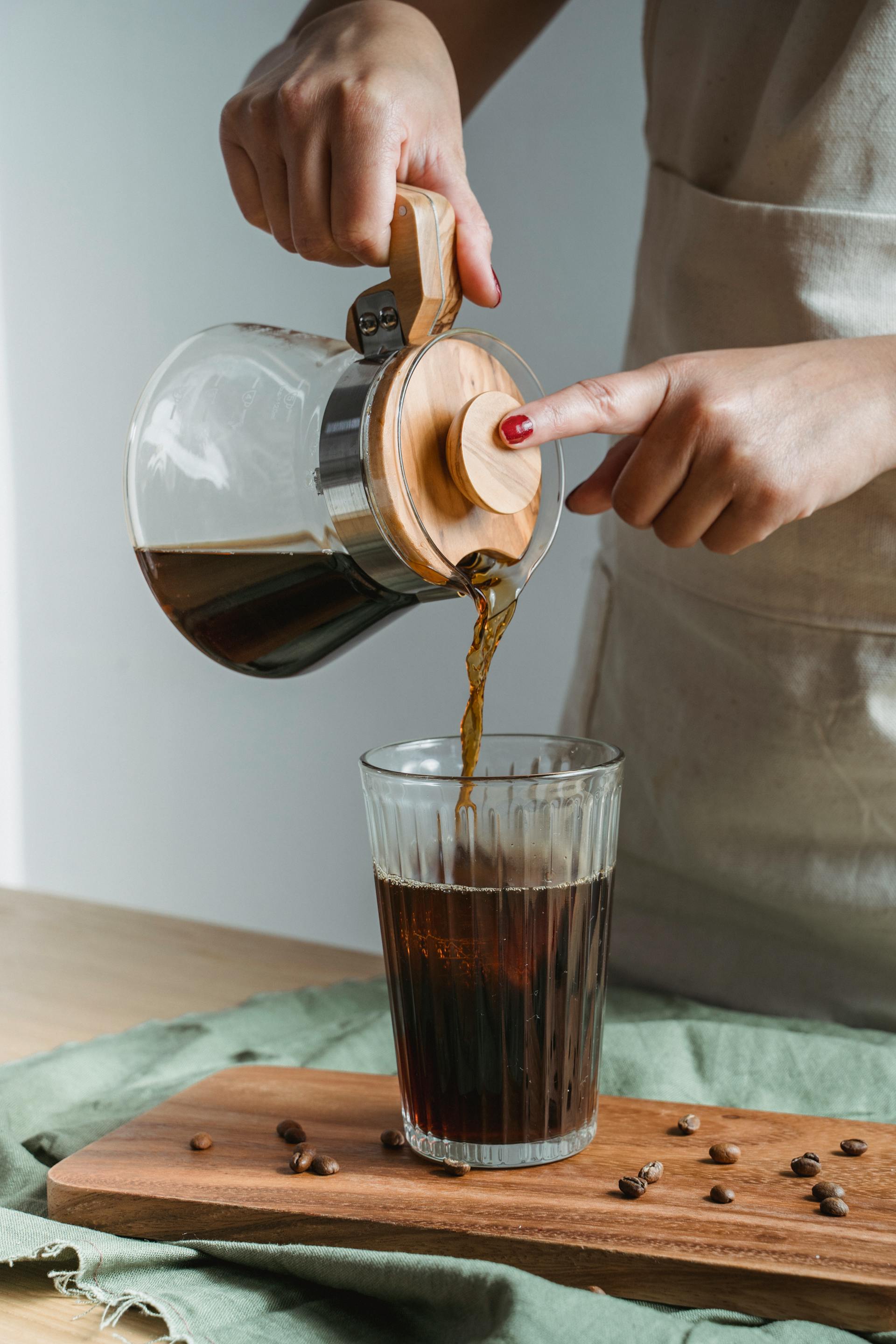 Una mujer sirviendo café negro en un vaso | Fuente: Pexels