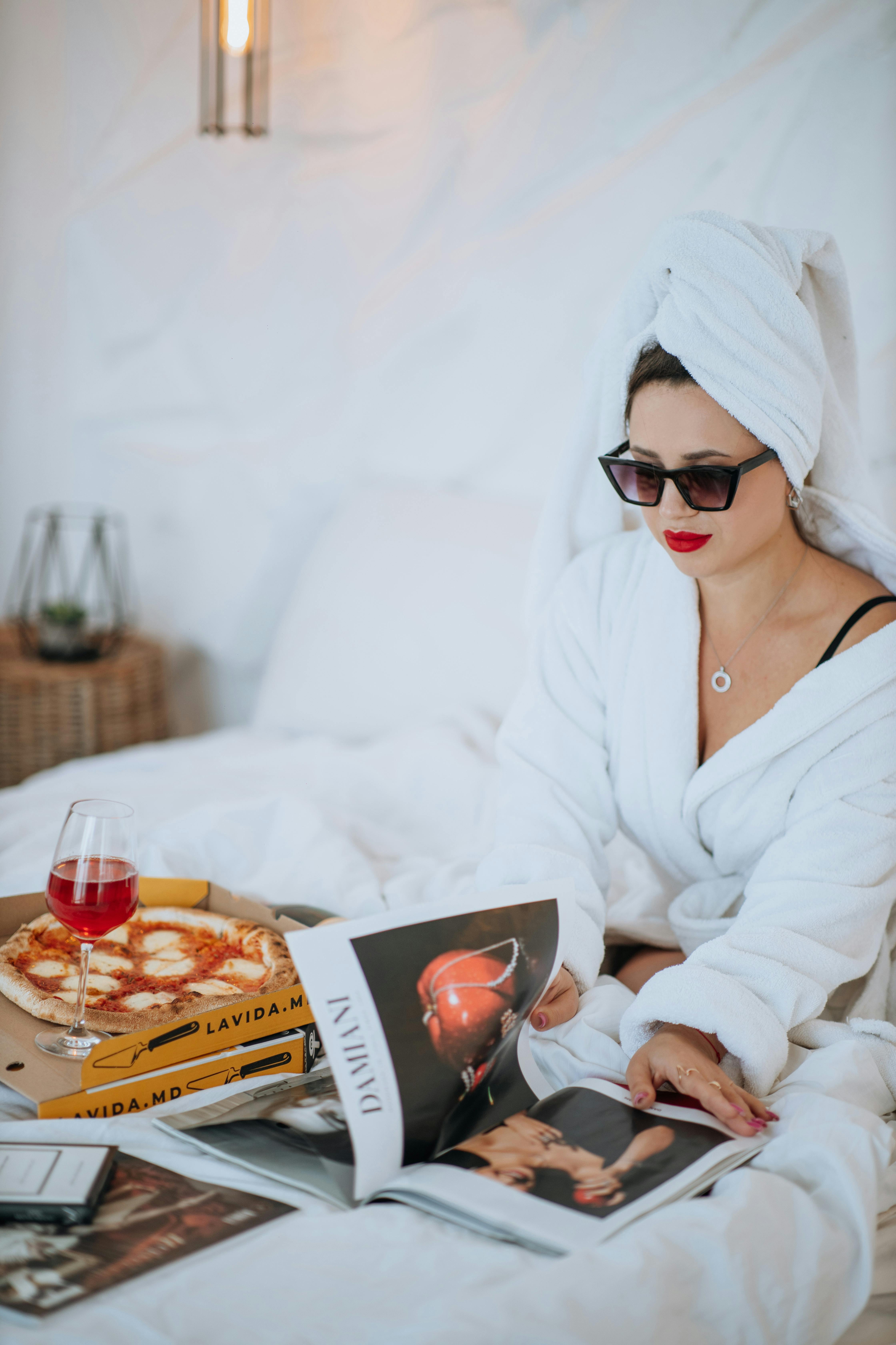Una mujer en bata comiendo pizza en la cama | Fuente: Pexels