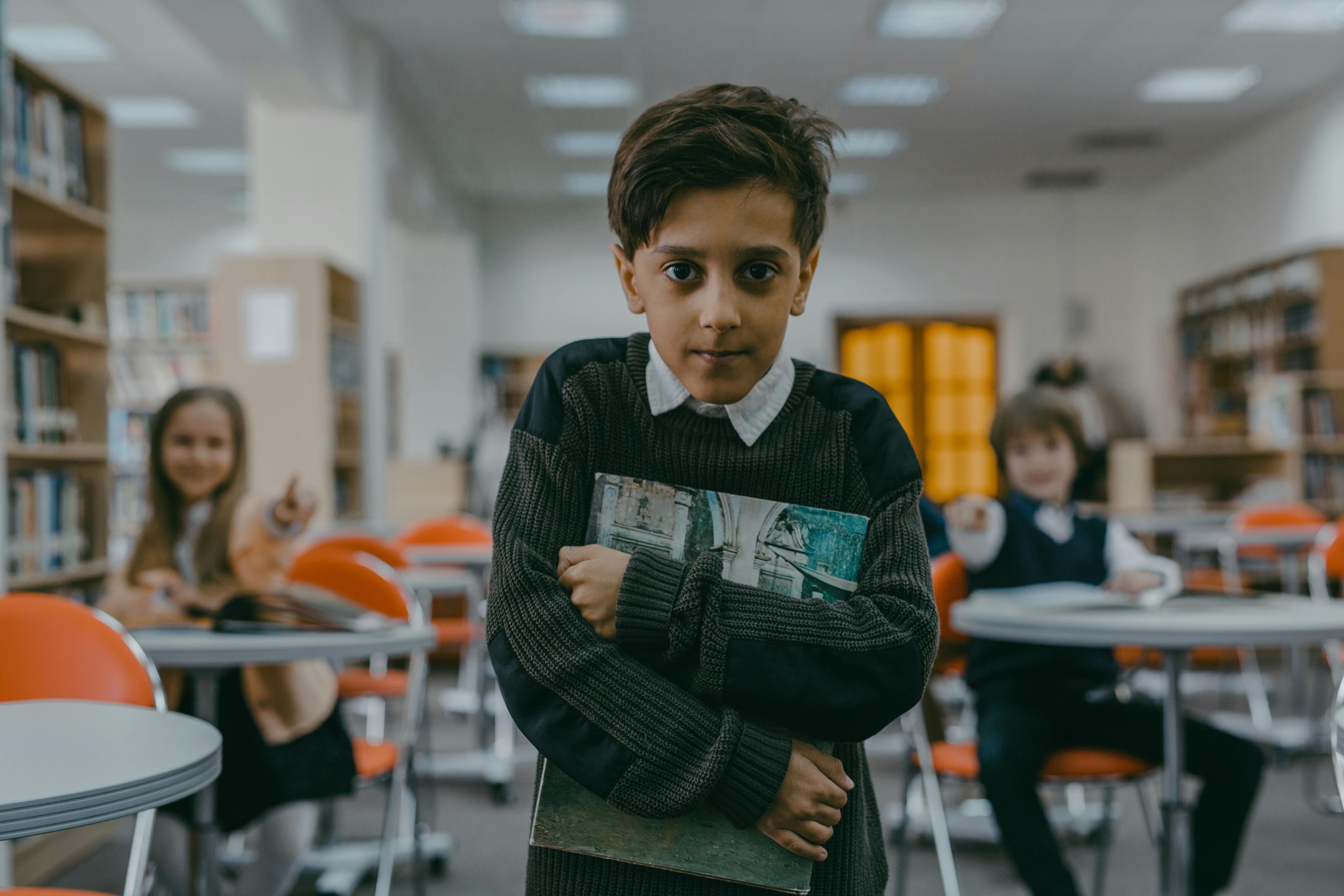 Un niño abrazando un libro con una pequeña sonrisa | Fuente: Pexels