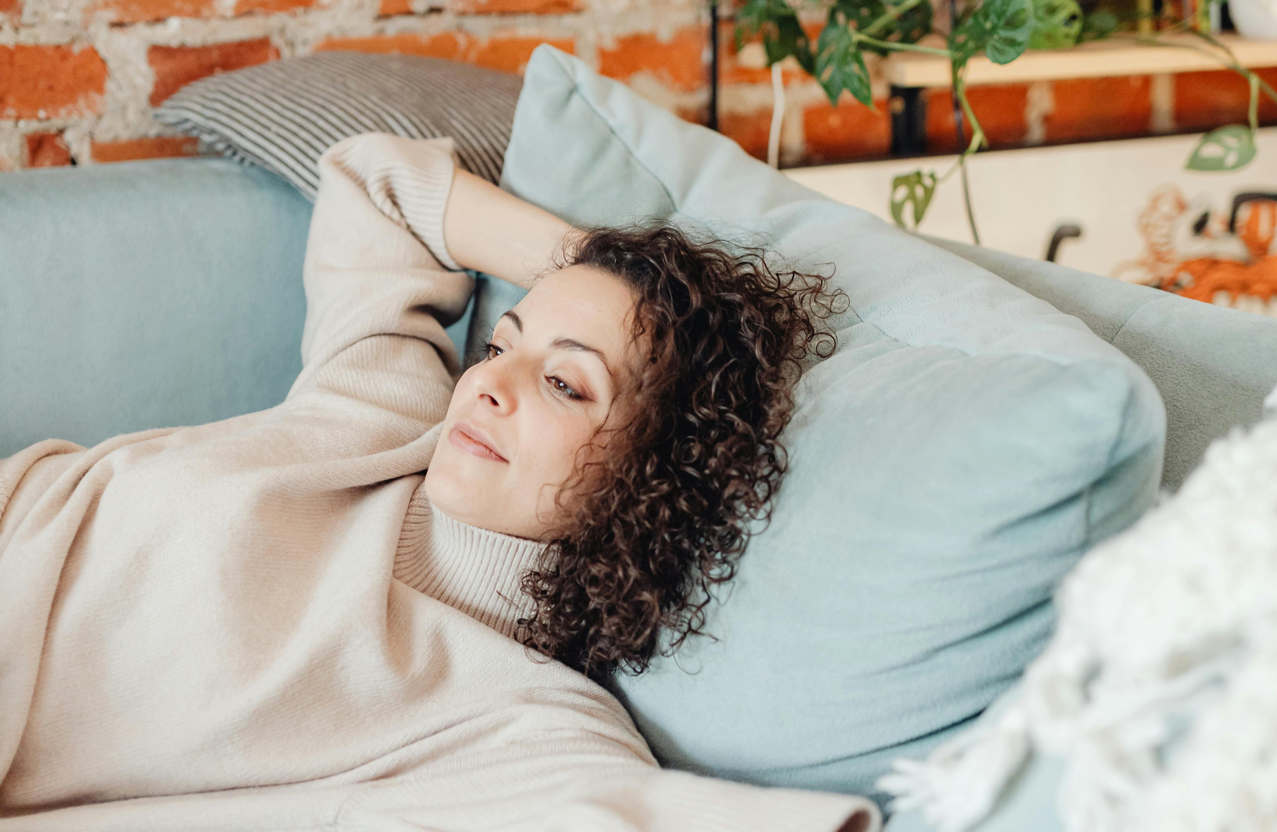 Una mujer tumbada en un sofá | Fuente: Pexels