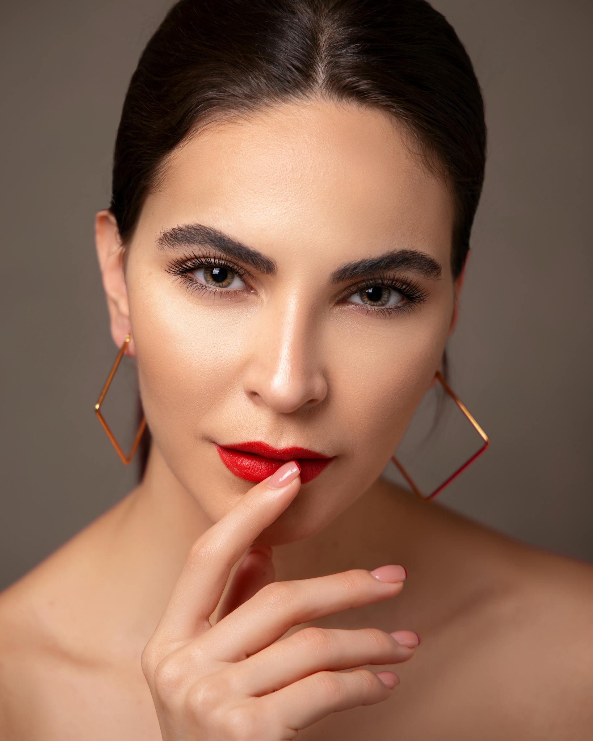 Una mujer con pintalabios rojo y pendientes | Fuente: Pexels