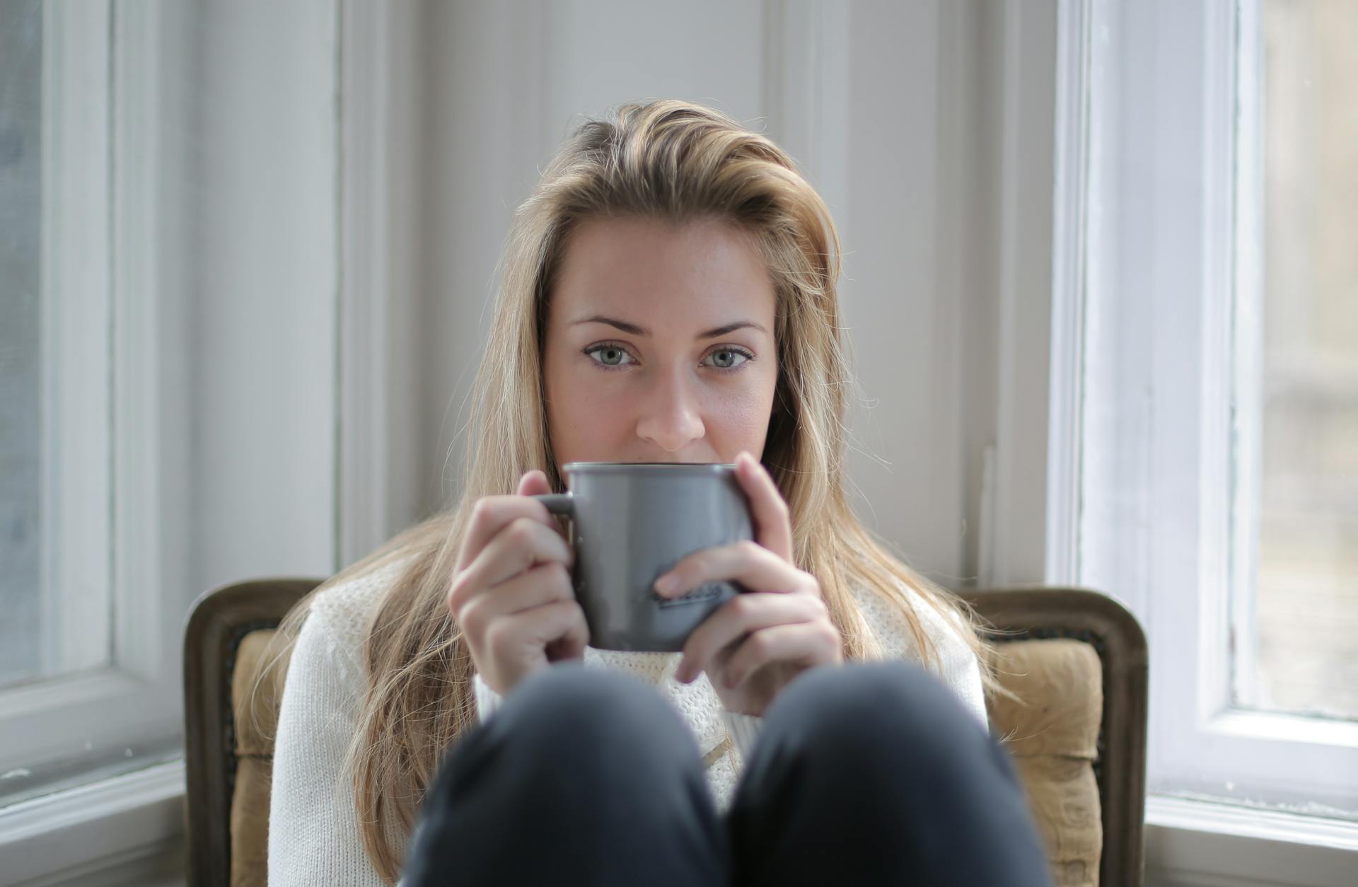 Una mujer sentada en una silla mientras sostiene una taza de café | Fuente: Pexels