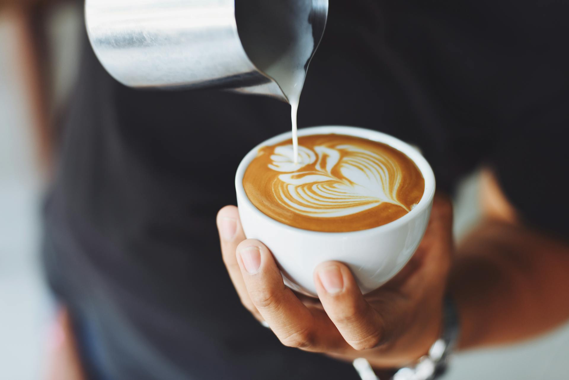 Un hombre echando crema en una taza de café | Fuente: Pexels