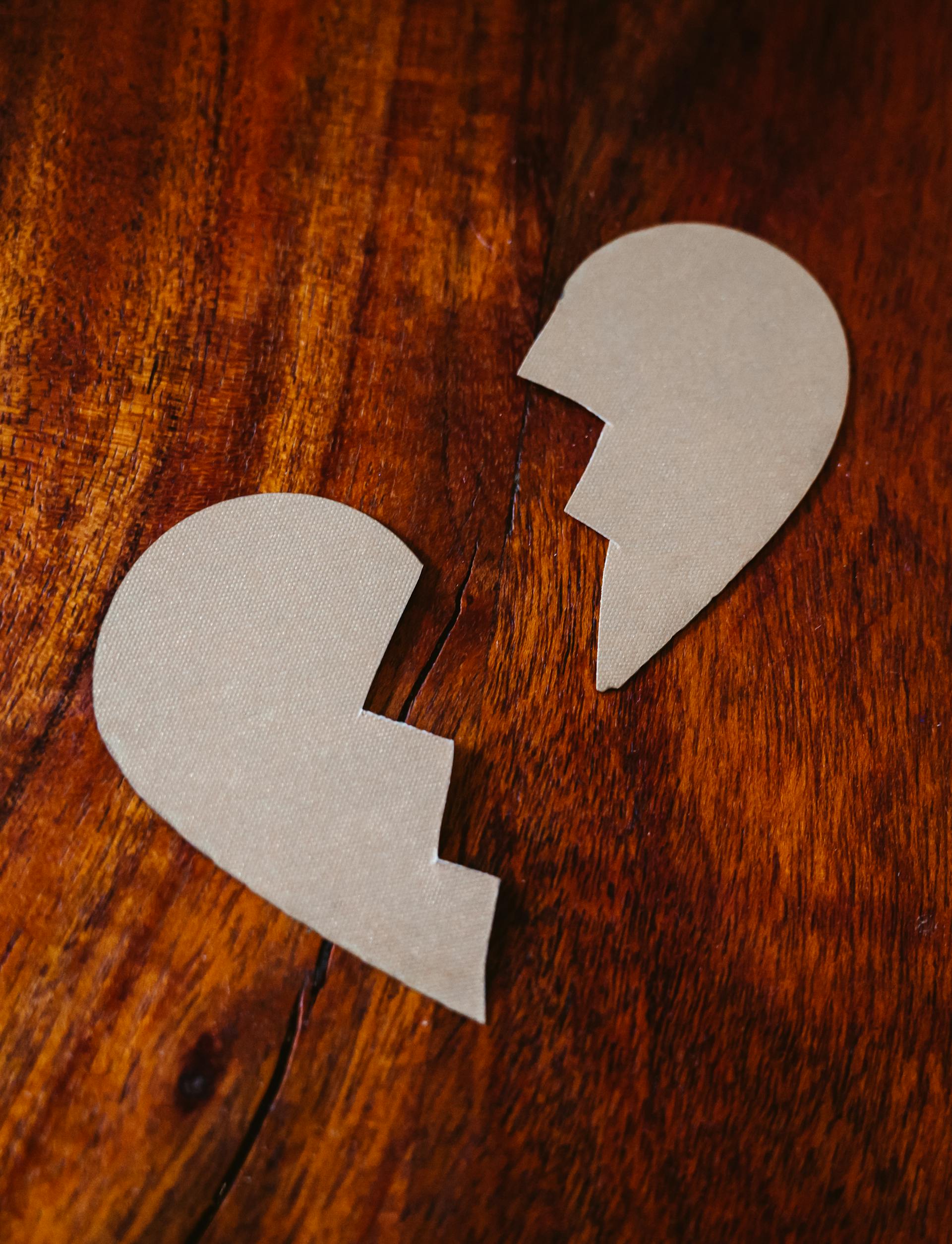 Piezas de cartón con forma de corazón roto sobre una superficie de madera | Fuente: Pexels