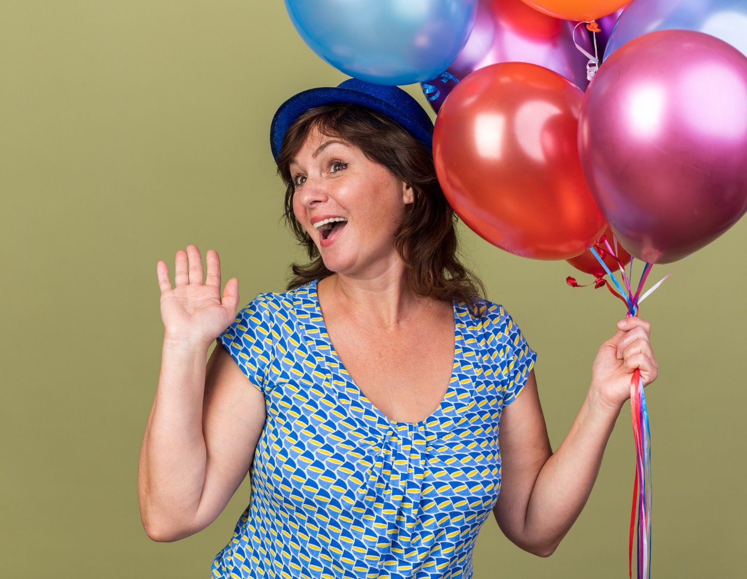 Una mujer mayor encantada sosteniendo globos | Fuente: Freepik