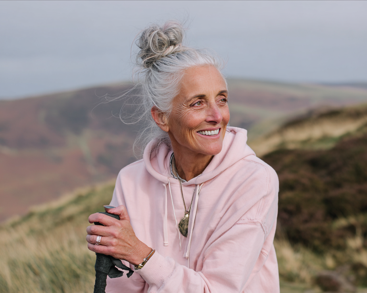 Una anciana sonriente con un suéter rosa | Fuente: Midjourney