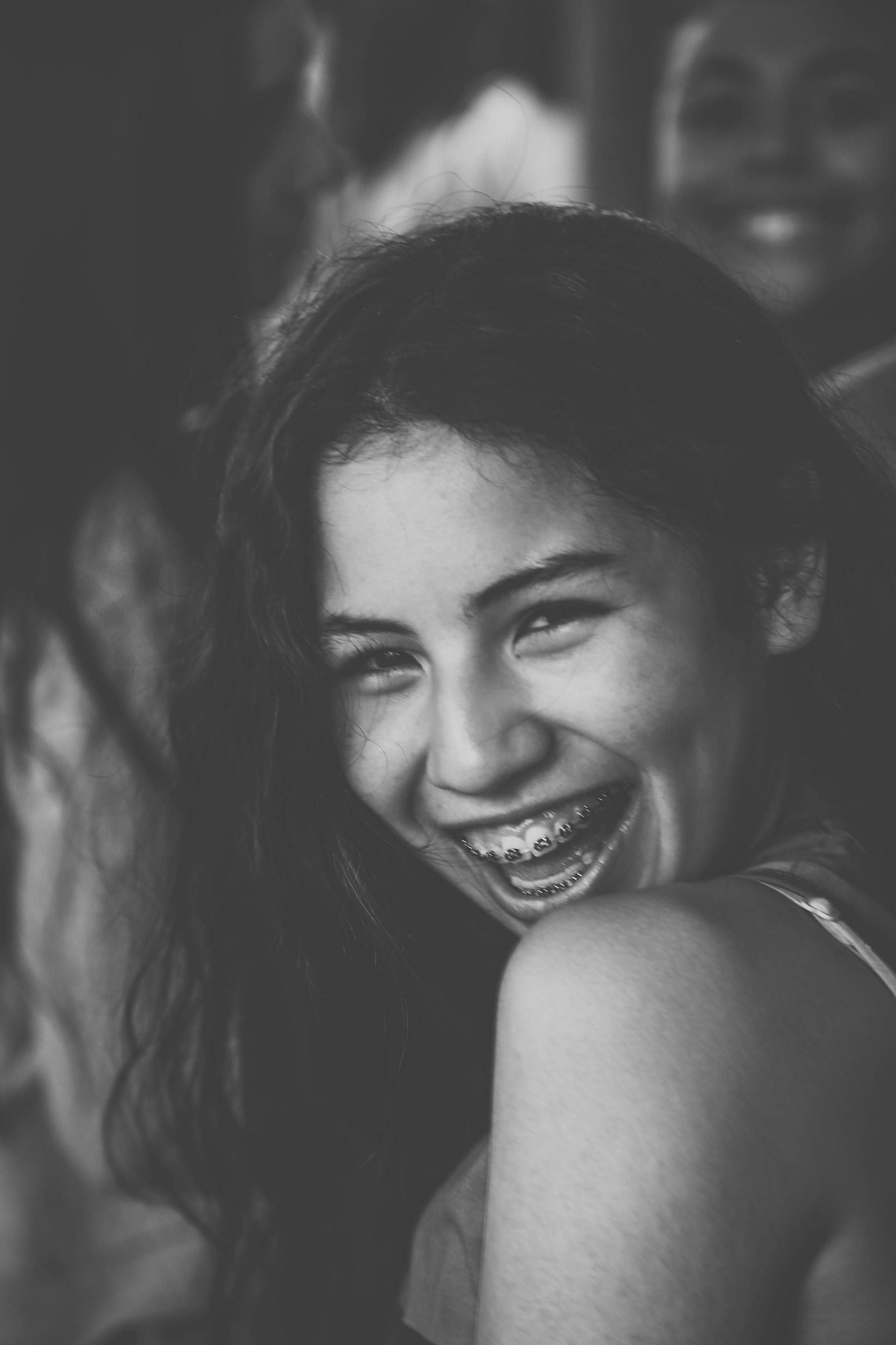 Foto em tons de cinza de uma jovem sorridente com aparelho ortodôntico | Fonte: Pexels