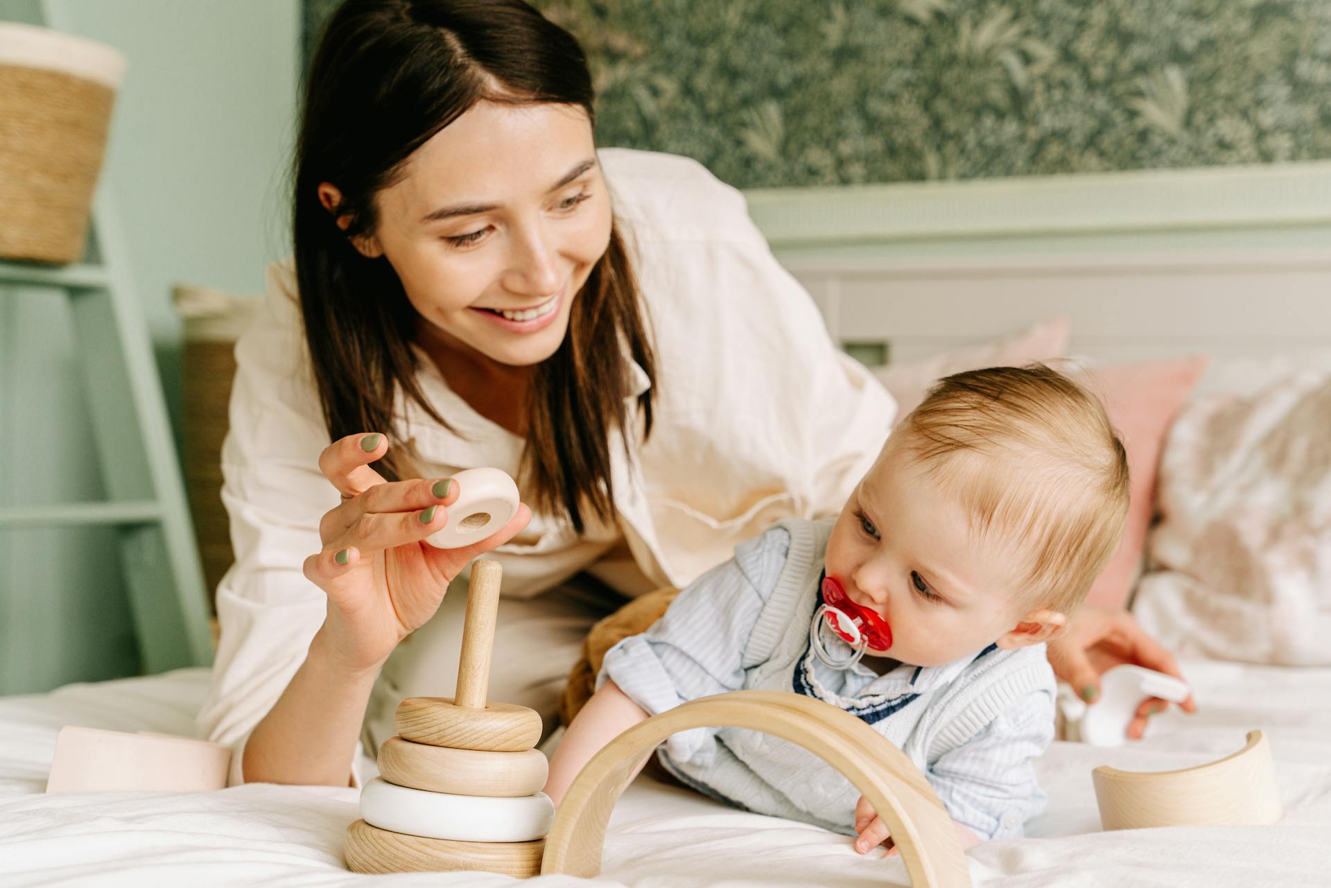 Una mujer juega con su bebé en una cama | Fuente: Pexels