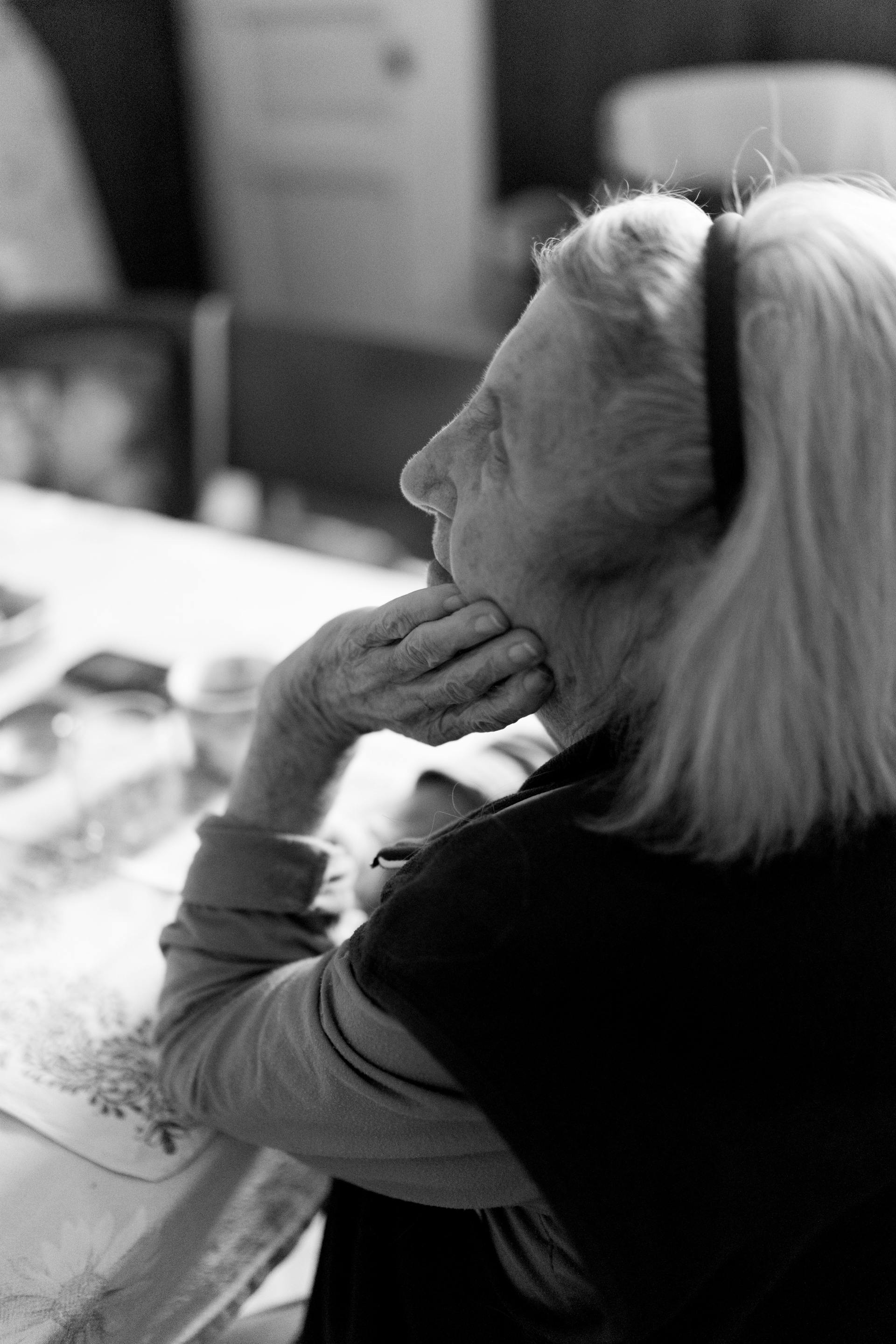 Imagen de perfil en blanco y negro de una anciana que apoya la barbilla en la mano y mira hacia arriba | Fuente: Pexels
