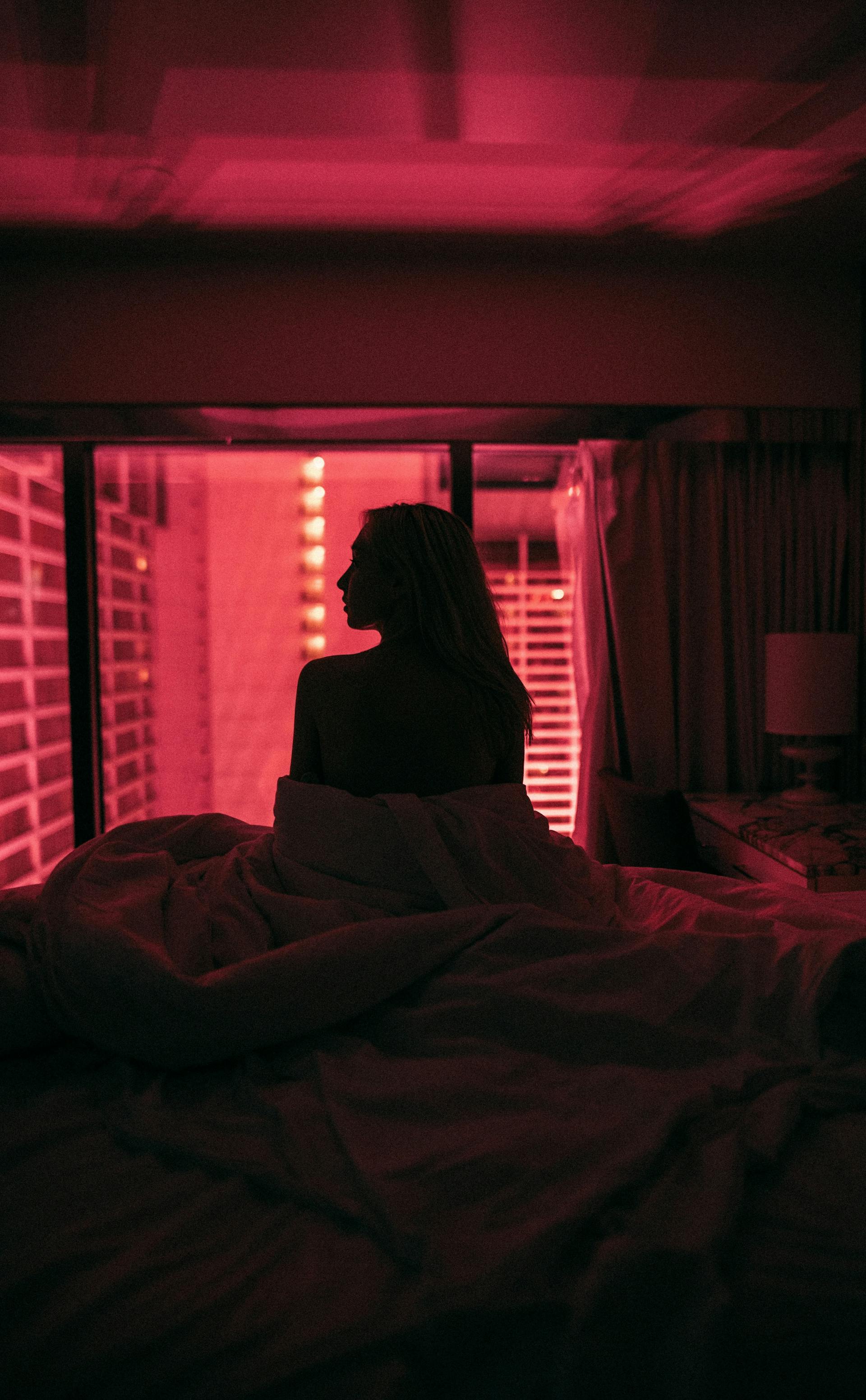 Una mujer sentada en la cama por la noche | Fuente: Pexels