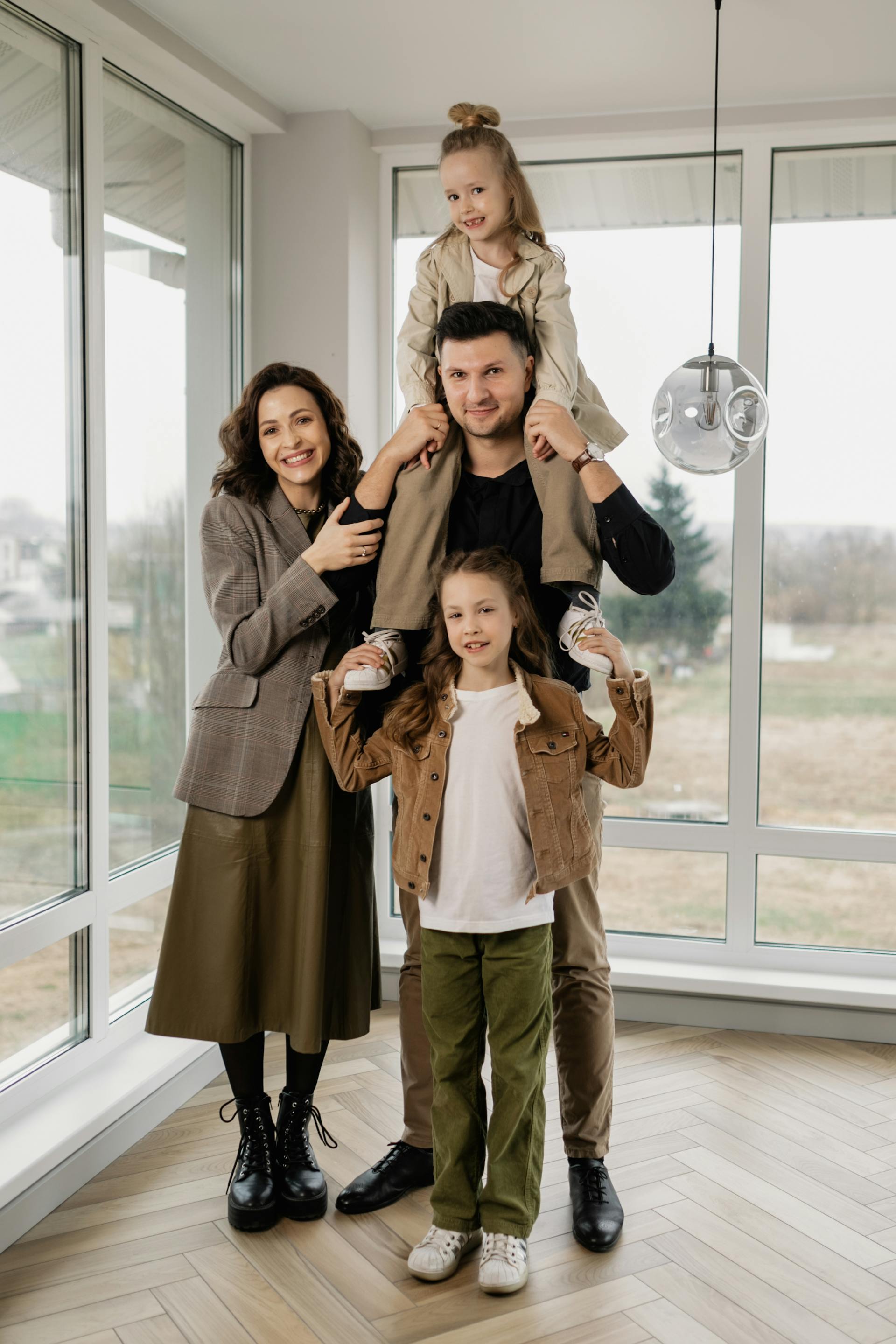 Un hombre lleva a una niña a hombros junto a su mujer y su hija | Fuente: Pexels