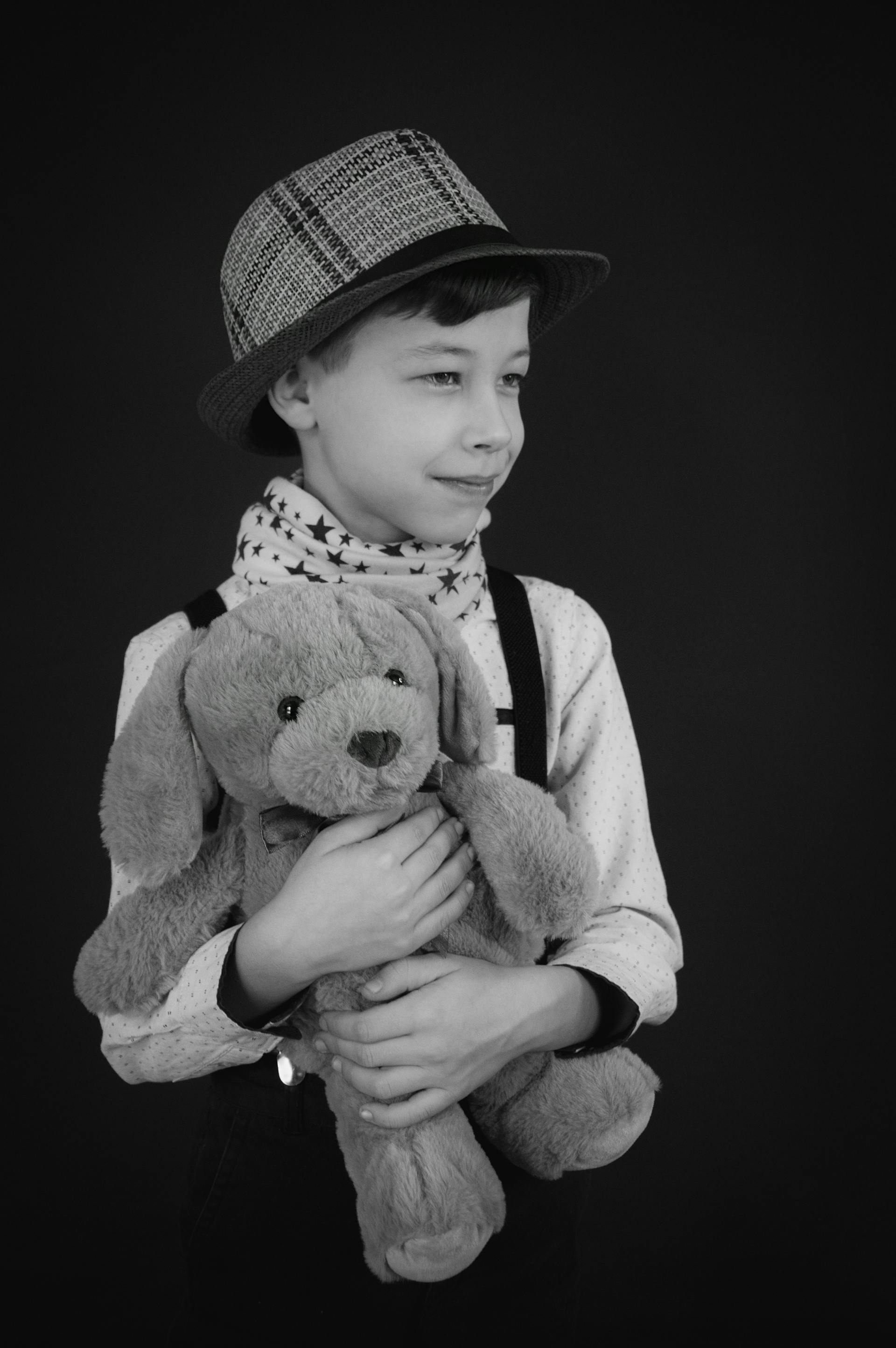 Foto en escala de grises de un niño sosteniendo un oso de peluche | Fuente: Pexels