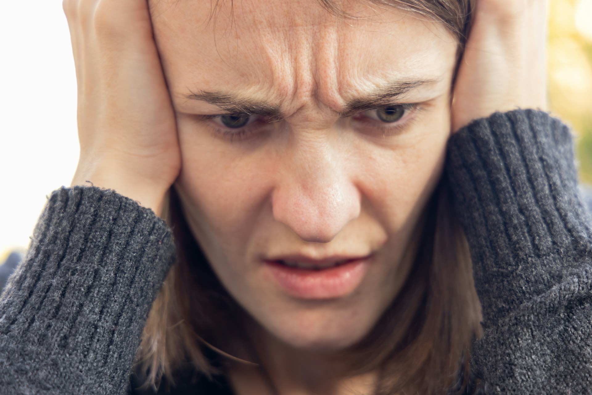 Una mujer apoya la cabeza en las manos mientras frunce el ceño | Fuente: Unsplash