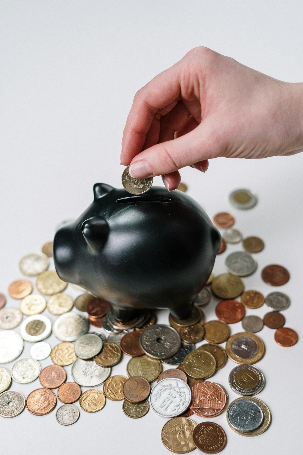 Primer plano de una mujer metiendo una moneda en una alcancía | Fuente: Pexels