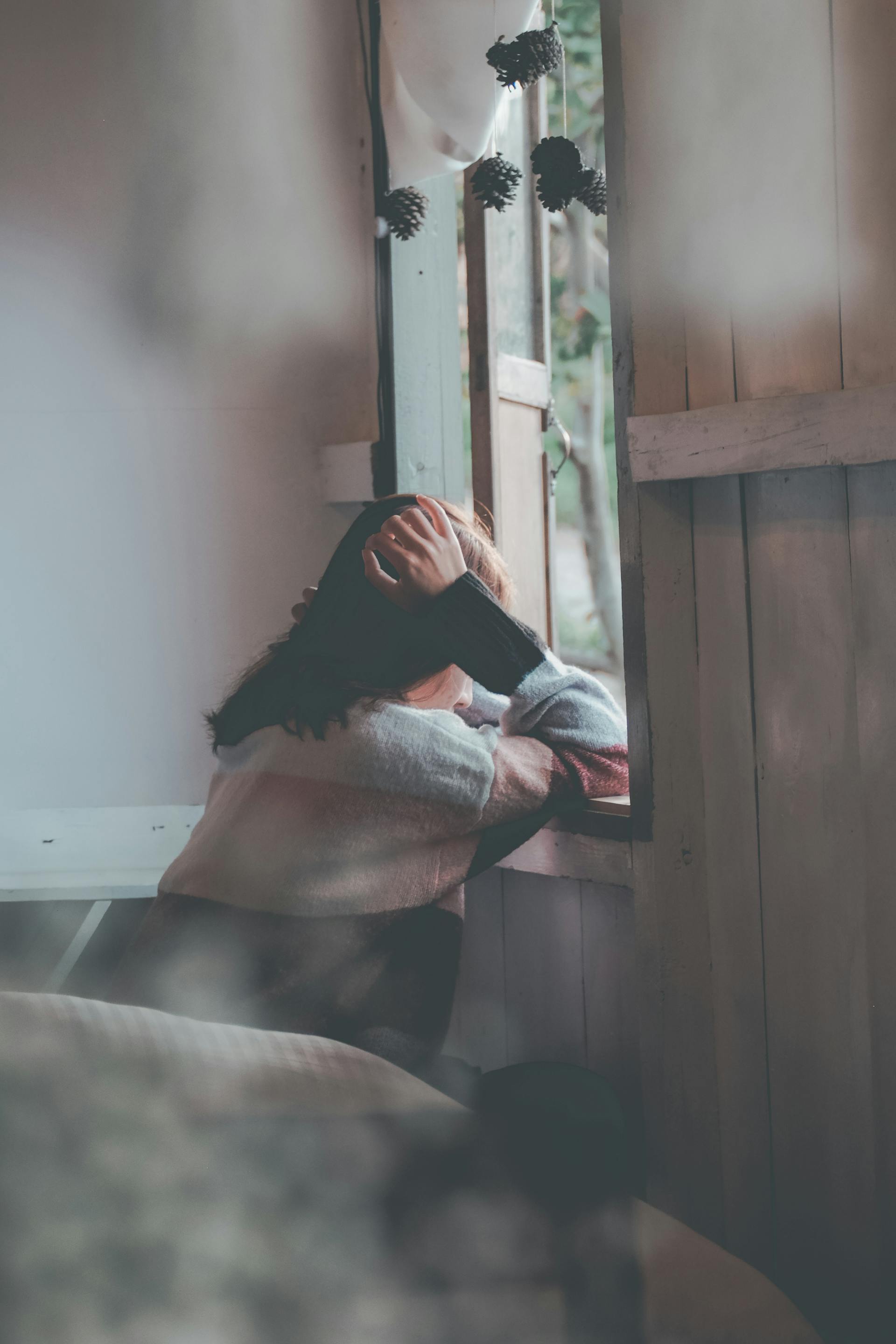 Vista trasera de una mujer apoyada en una ventana de madera | Fuente: Pexels
