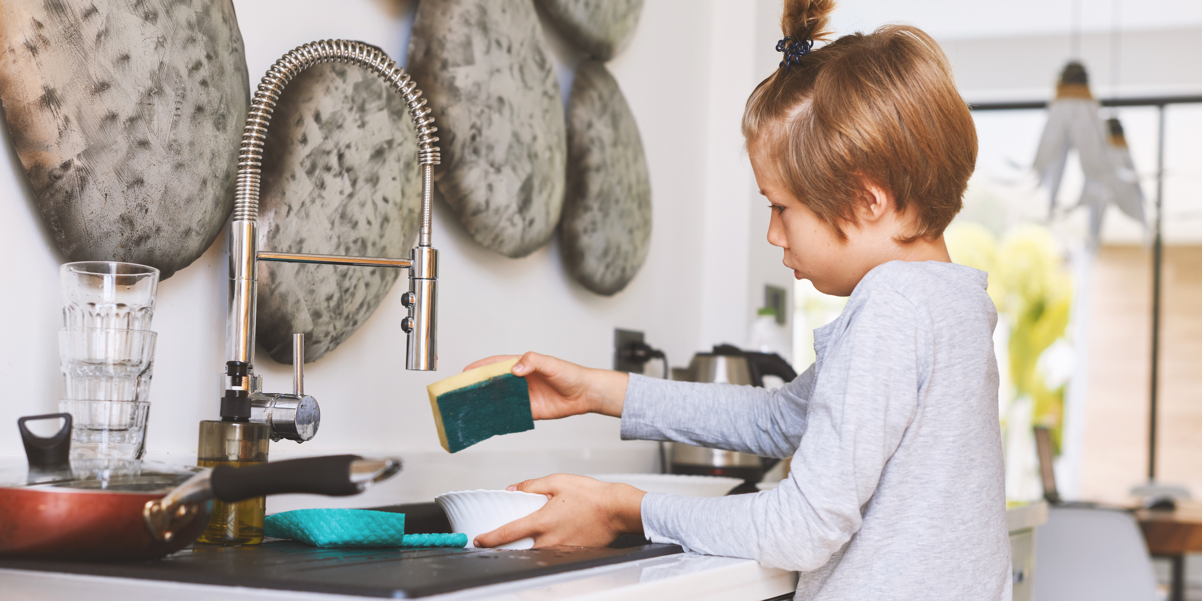 Un niño lavando los platos | Fuente: Shutterstock