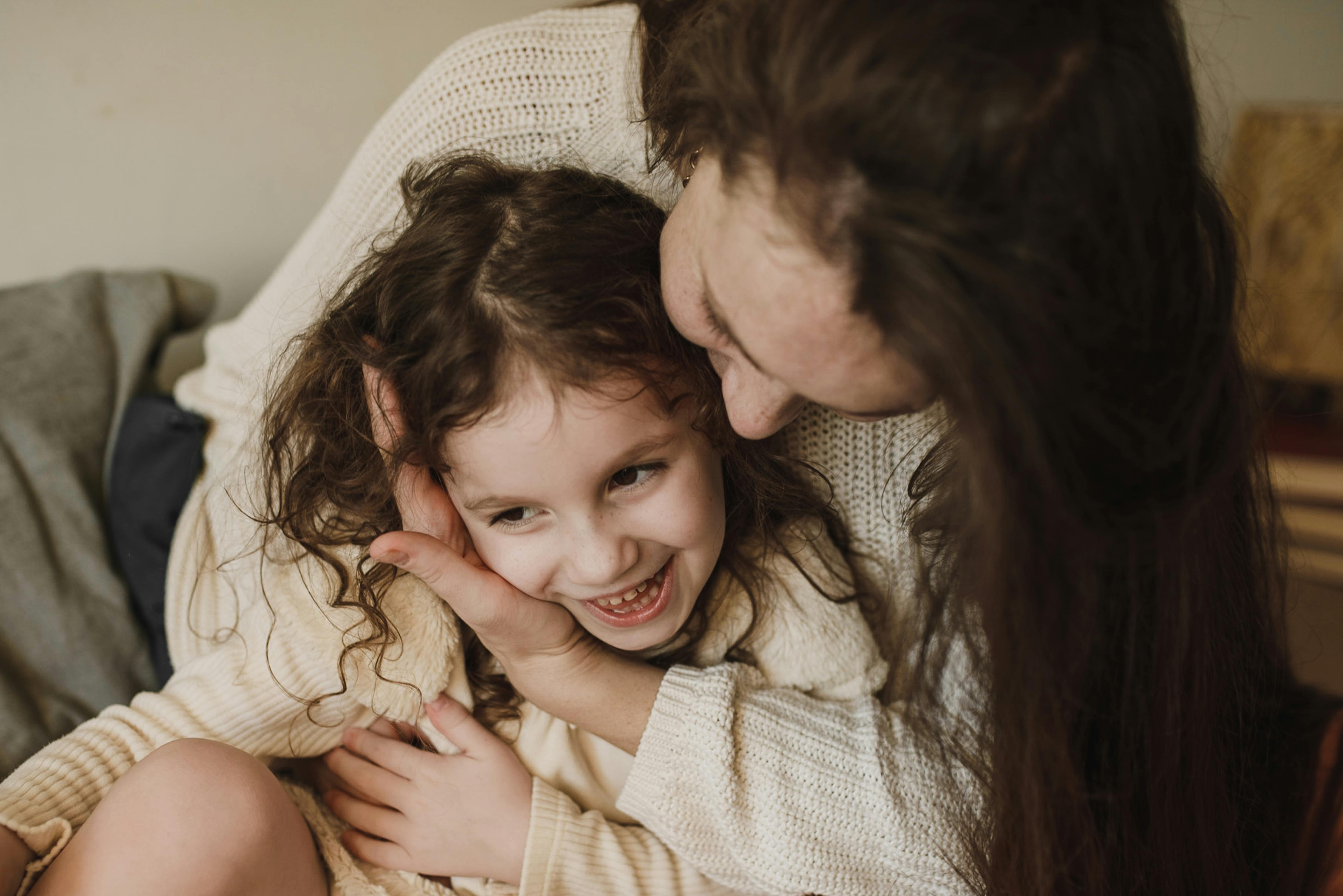 Una niña feliz sentada en el regazo de su madre | Fuente: Pexels