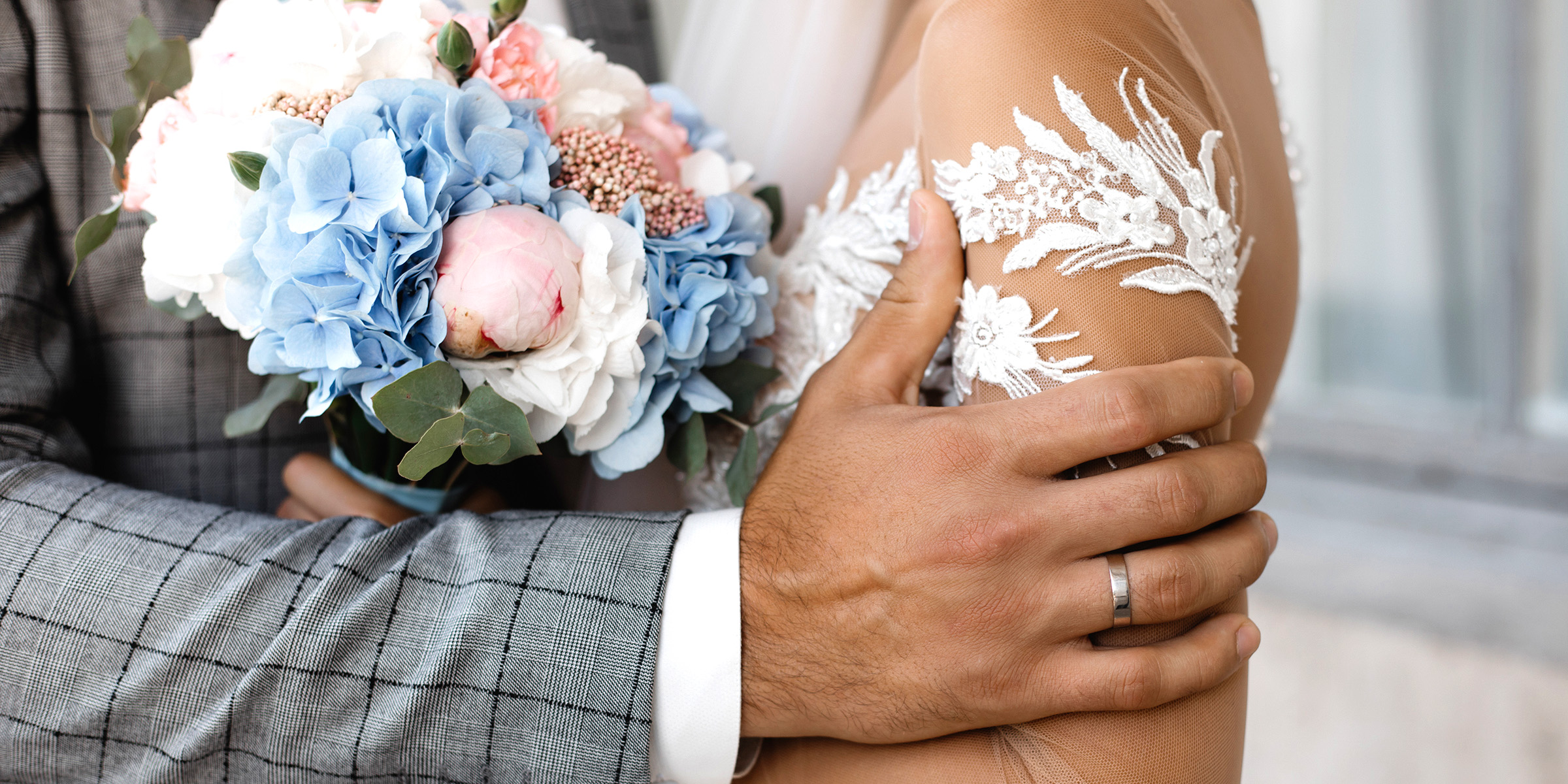 Un novio sostiene suavemente a su novia, sus manos envueltas en un ramo de flores pastel | Fuente: Freepik