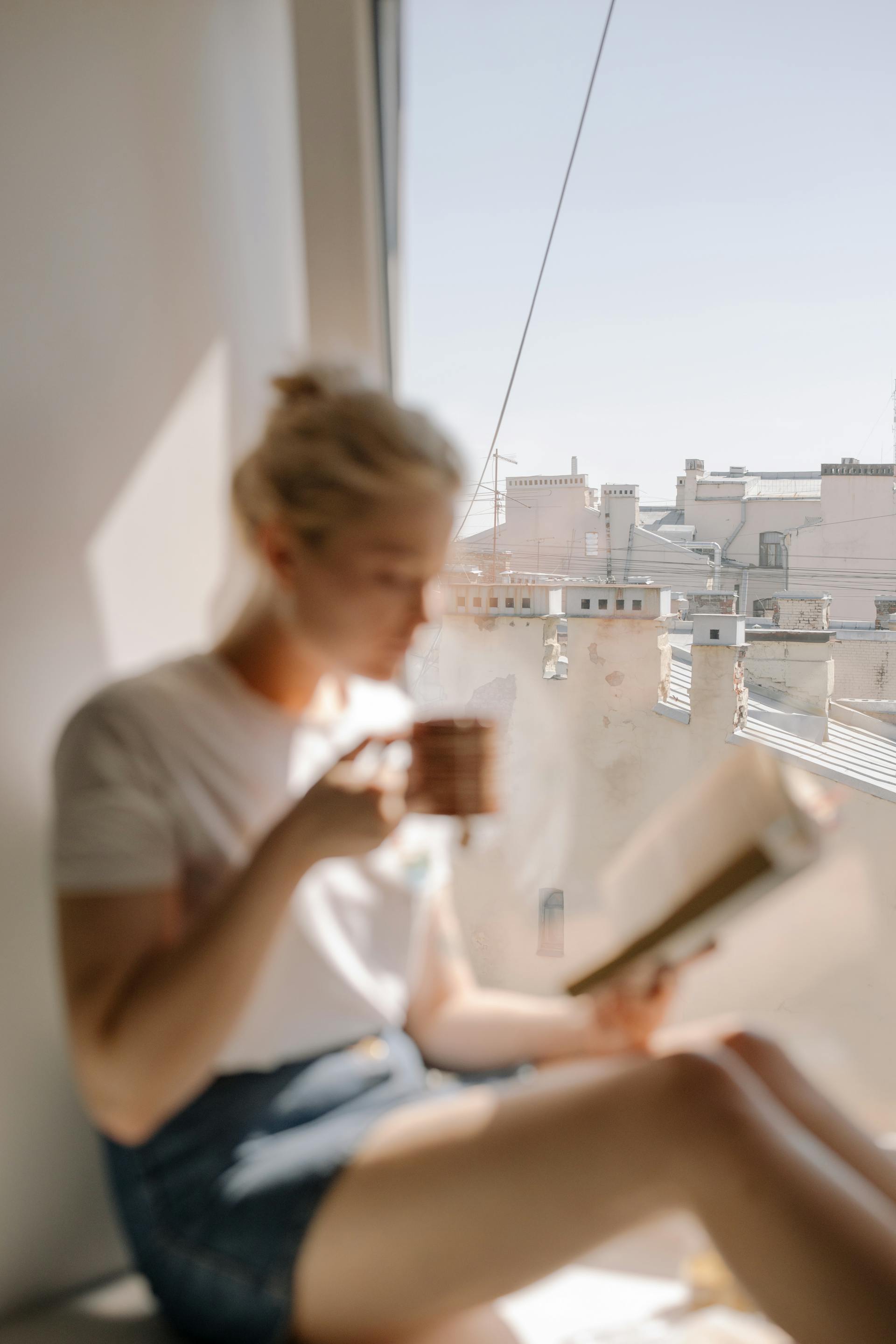 Una mujer bebiendo café cerca de la ventana de un apartamento | Fuente: Pexels