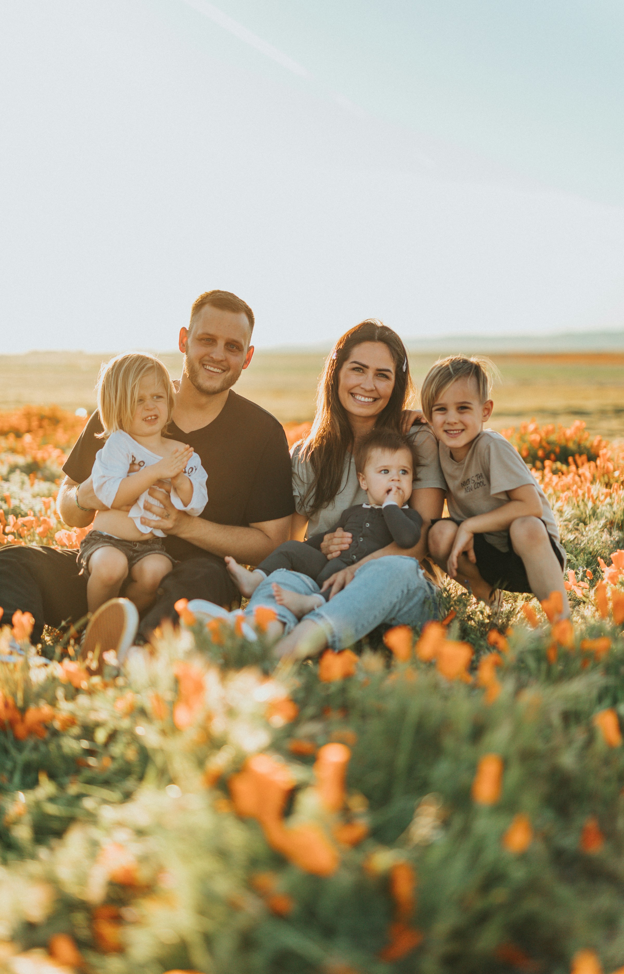 Una pareja feliz con sus tres hijos sentados juntos en un campo cubierto de hierba | Fuente: Unsplash