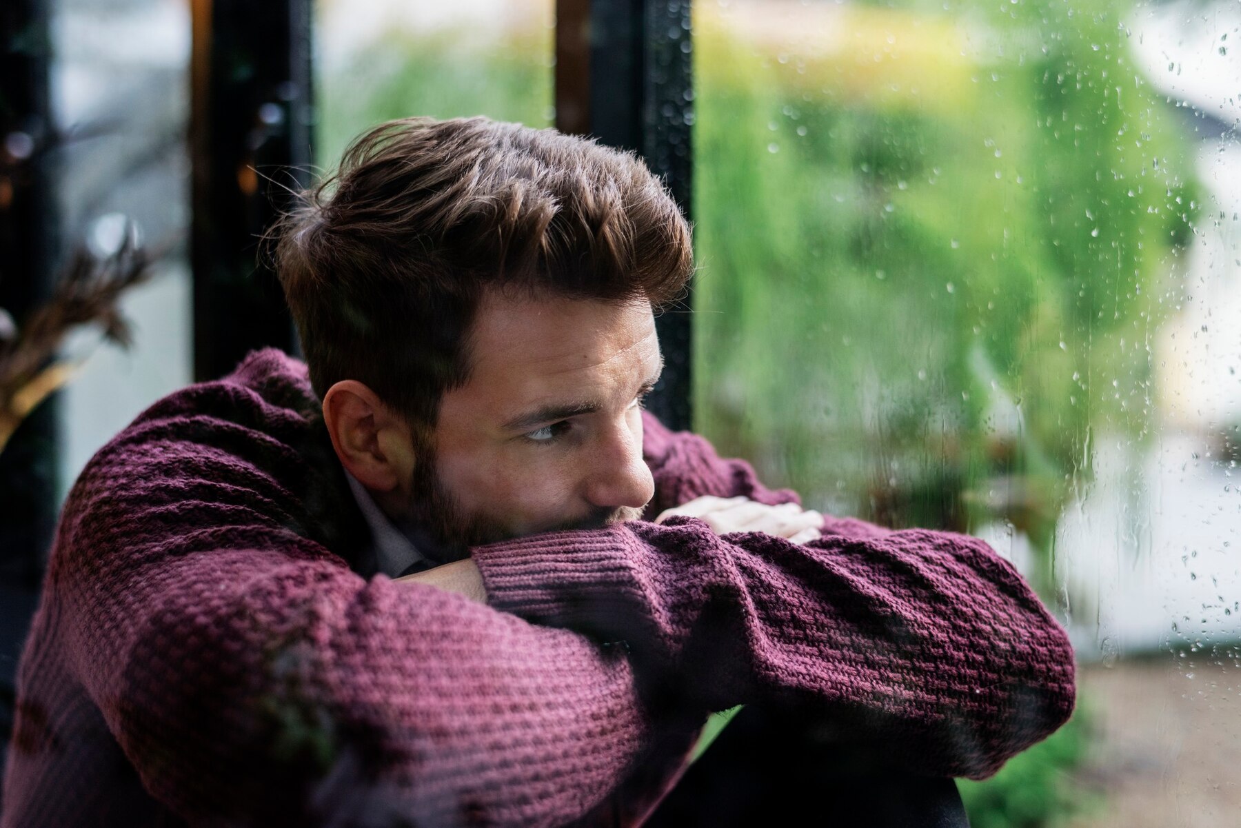 Un hombre triste mirando por la ventana | Fuente: Freepik