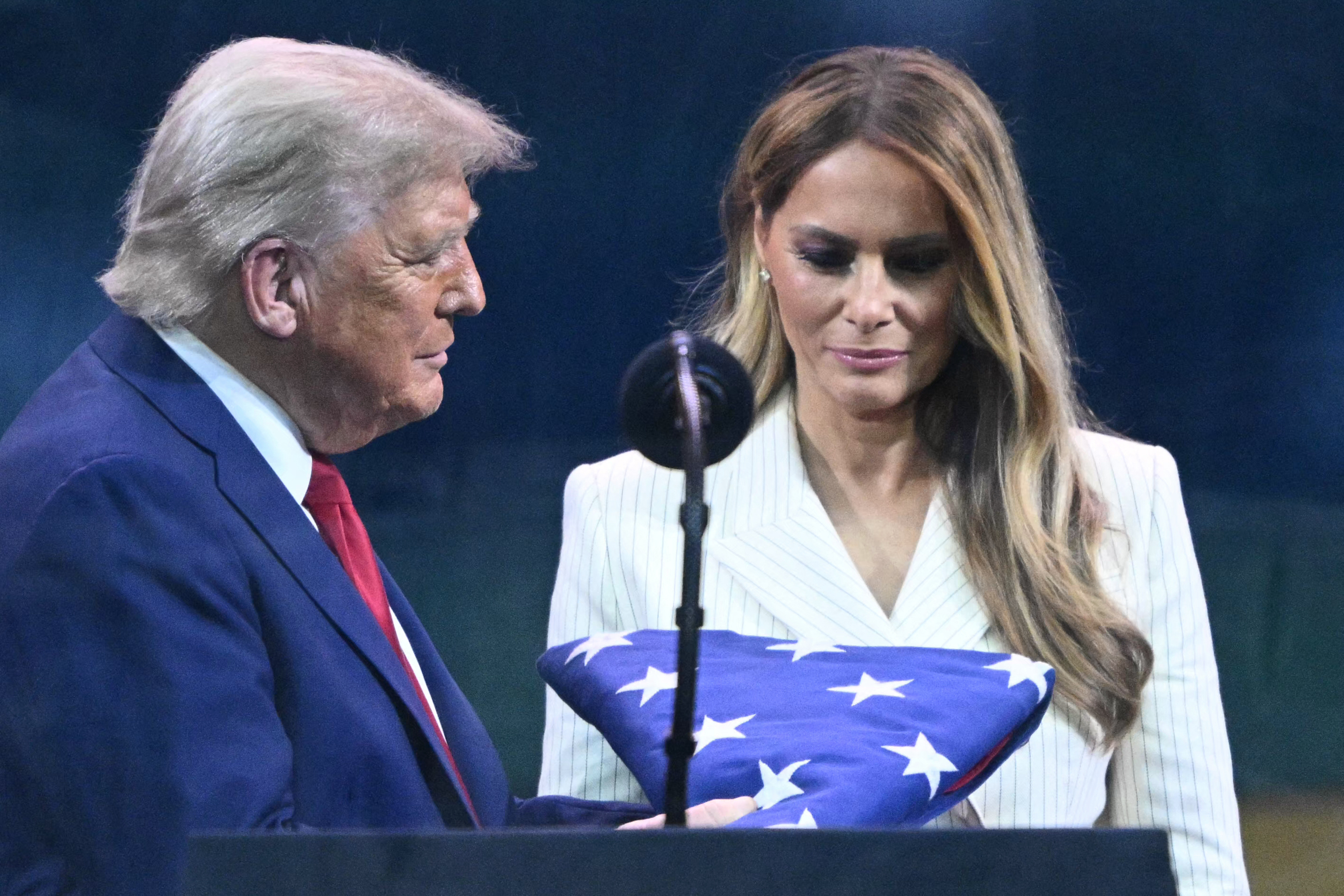 Donald y Melania Trump observan una bandera estadounidense entregada a Trump por un miembro de los Caballeros de Oro del Ejército el 14 de junio de 2025 | Fuente: Getty Images