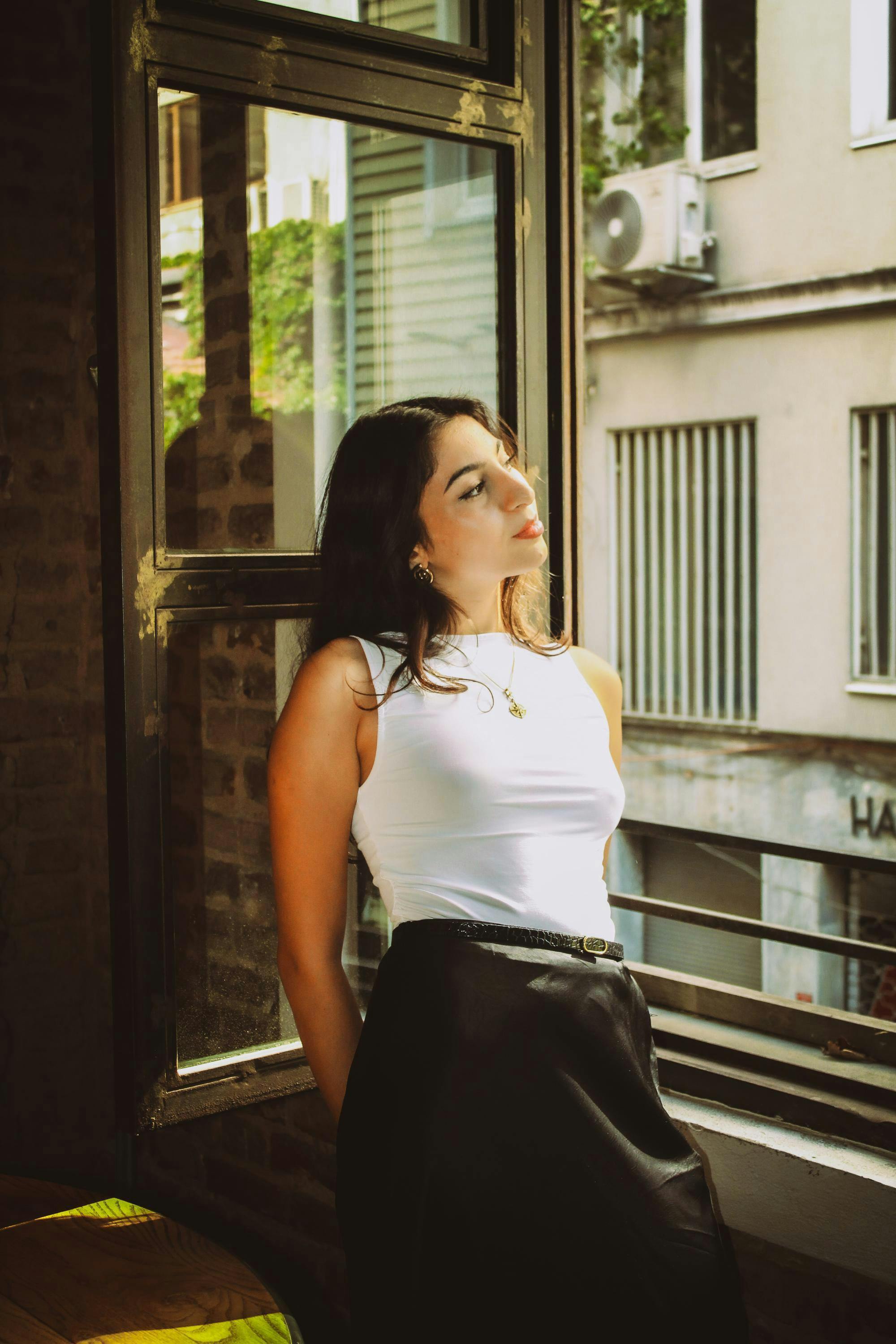 Mujer inclinada junto a la ventana | Fuente: Pexels