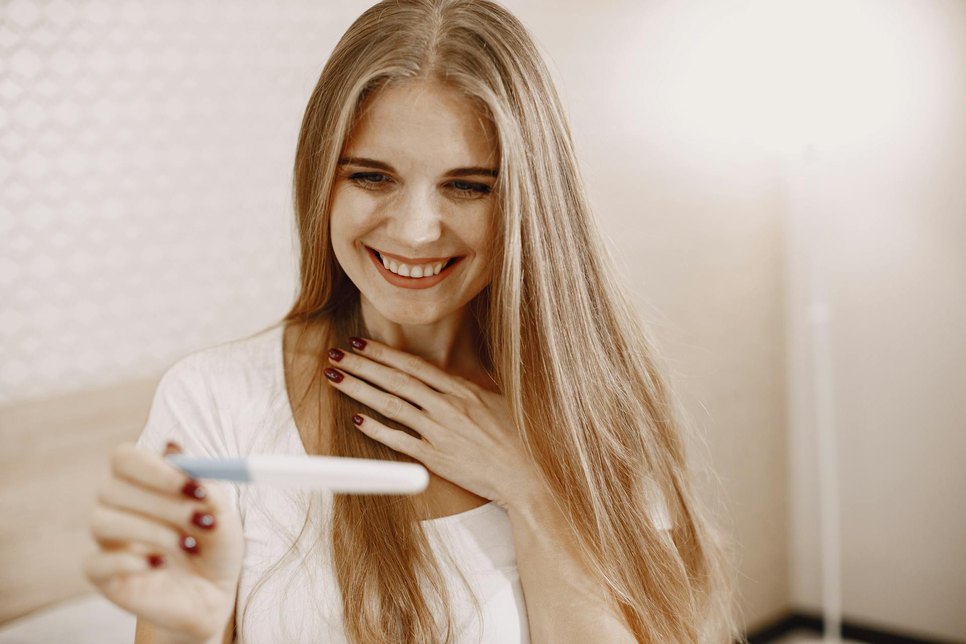 Una mujer encantada sosteniendo un kit de prueba de embarazo | Fuente: Pexels