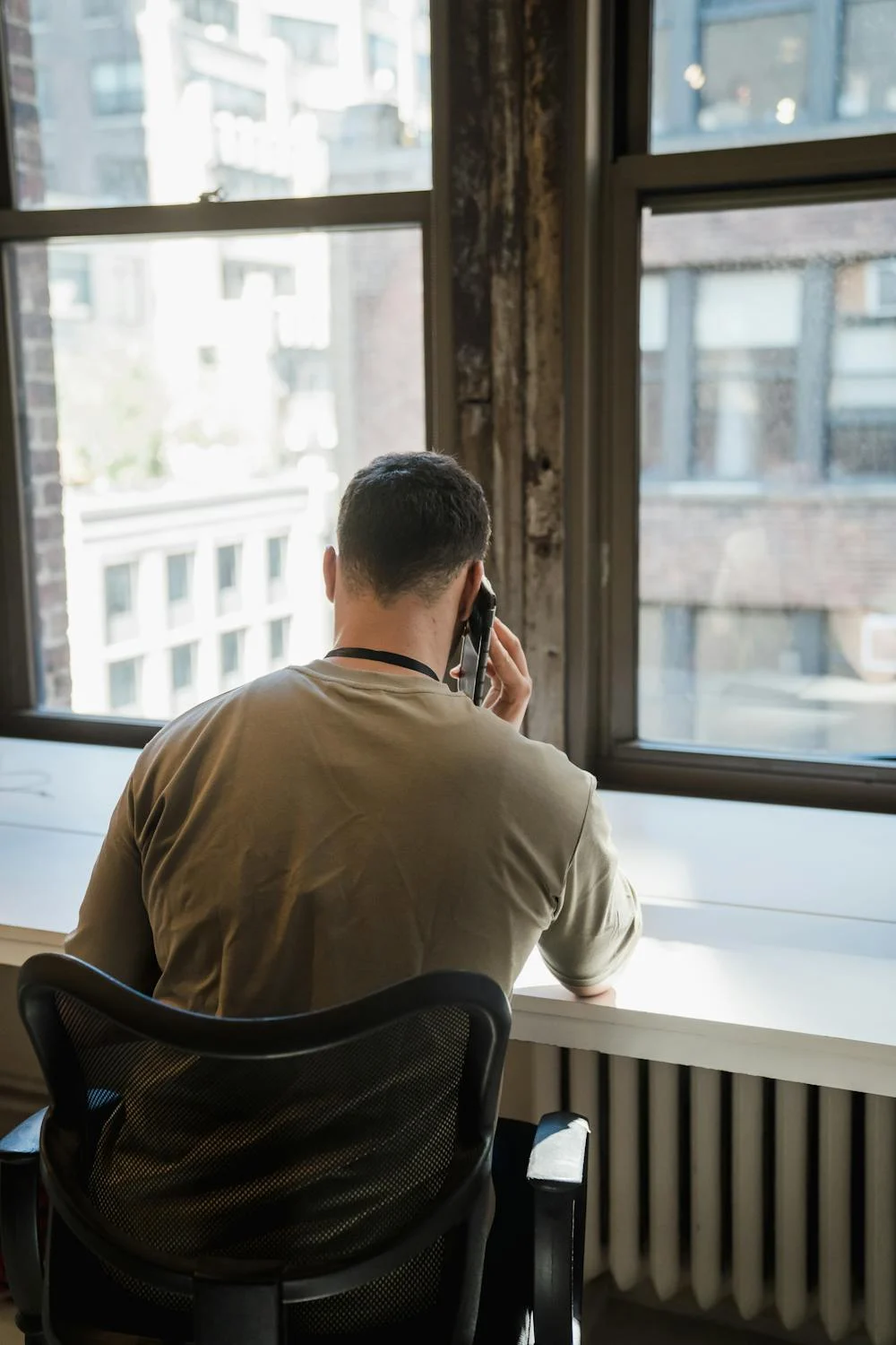 Un hombre hablando por teléfono en el salón de su casa | Fuente: Pexels